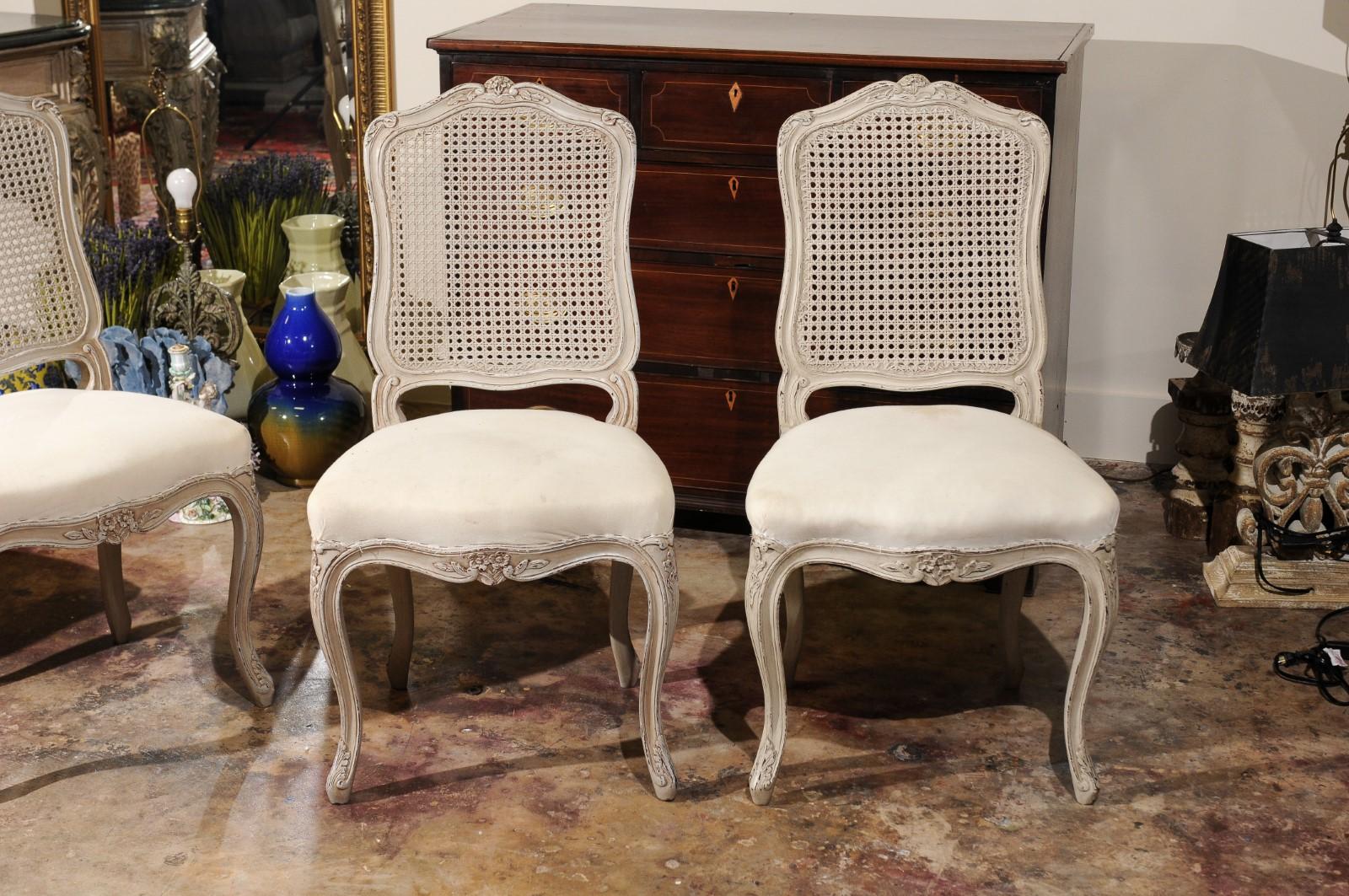 Four beautiful side chairs imported from Italy in the 1980s. They are of solid mahogany painted a grayish white color. The caned backs have carving on the top and on the cabriole legs. Perfect condition. Seats covered in muslin so will need to be