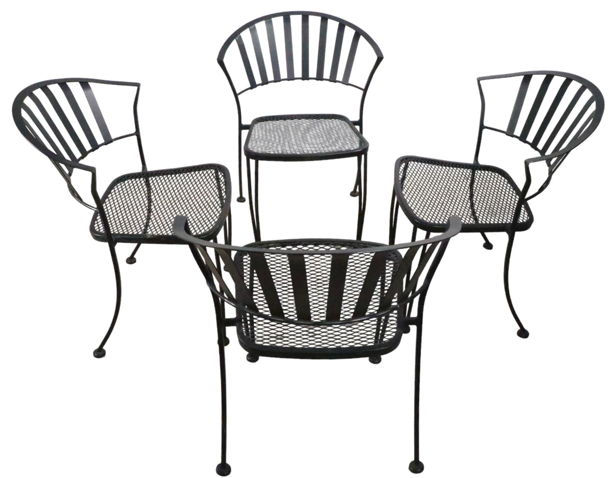 Set of four wrought iron and metal mesh garden, patio, poolside dining chairs. Te chairs have metal strap backs, and metal mesh seats. All four are in very fine, original, clean and ready to use condition, showing only light cosmetic wear, normal