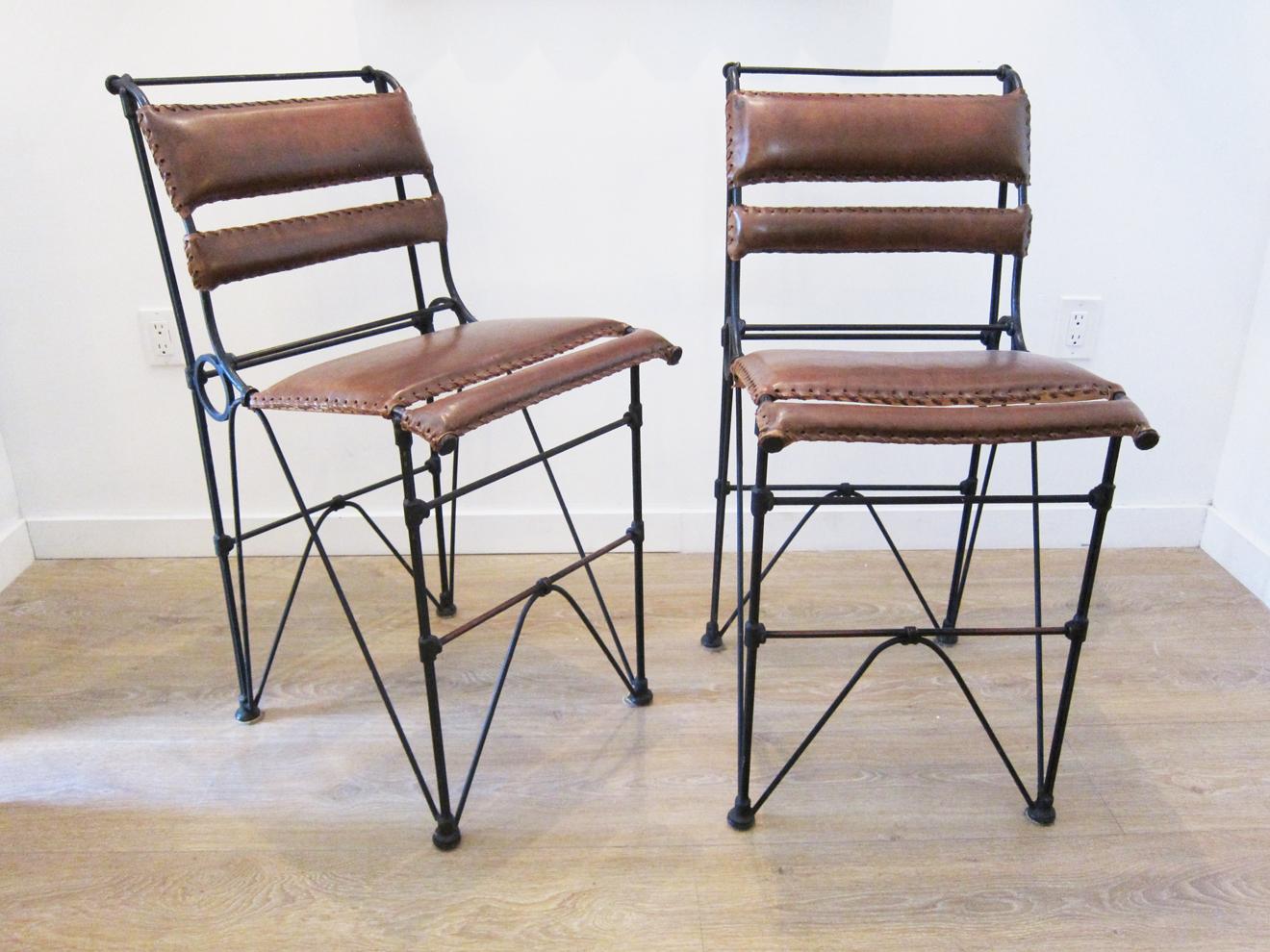 Set of four vintage iron and stitched leather bar stools, 
 Very detailed wrought iron base
 Hand stitched caramel burnt leather with sewn edges, nice patina from age and usage
 Can be sold in pairs or a group of four.


 