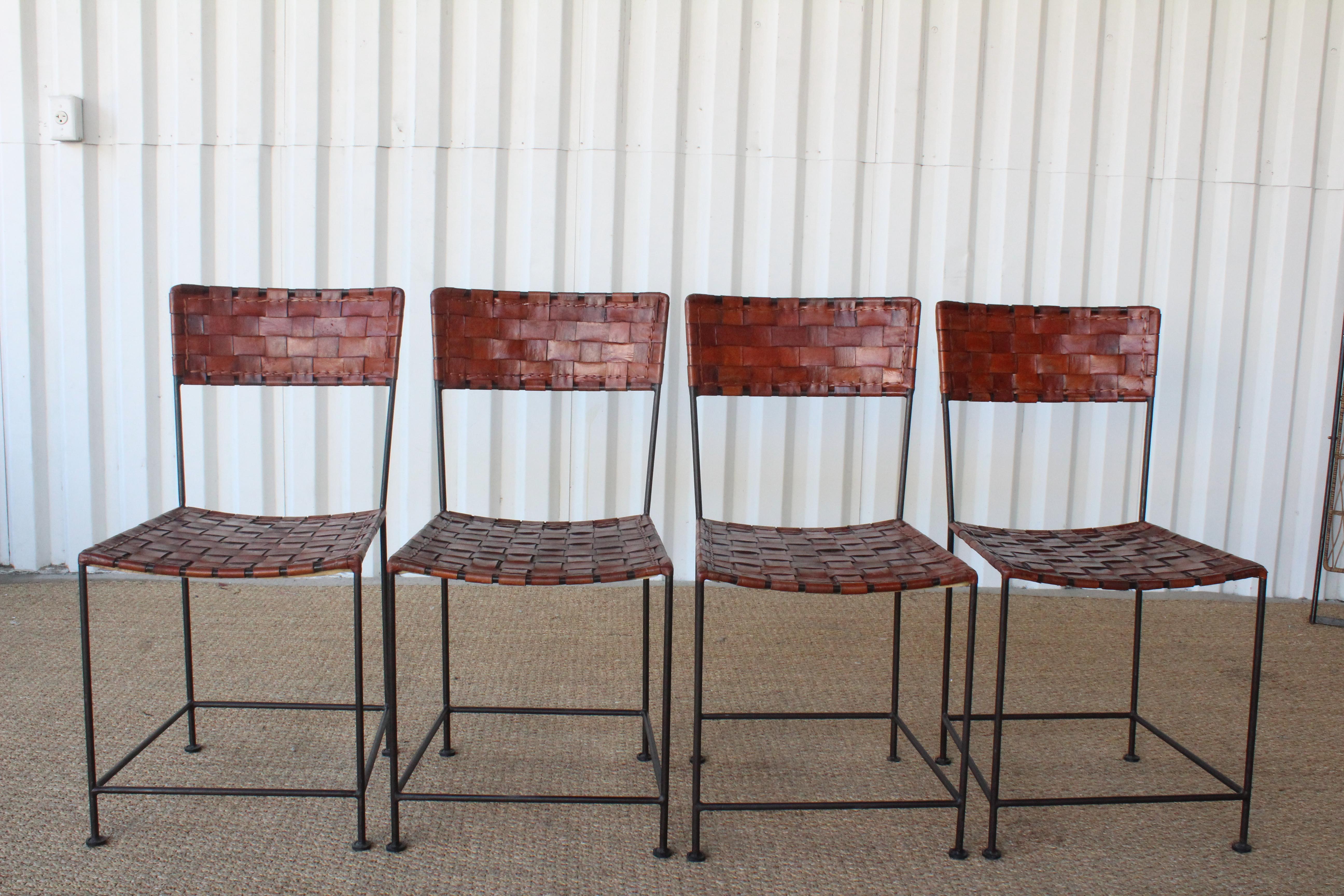 A set of four vintage iron framed dining chairs with leather woven seats, France, 1960s. Each chair is in good condition with the original woven leather backs and seats. Leather shows a beautiful patina. Sold as a set of four.