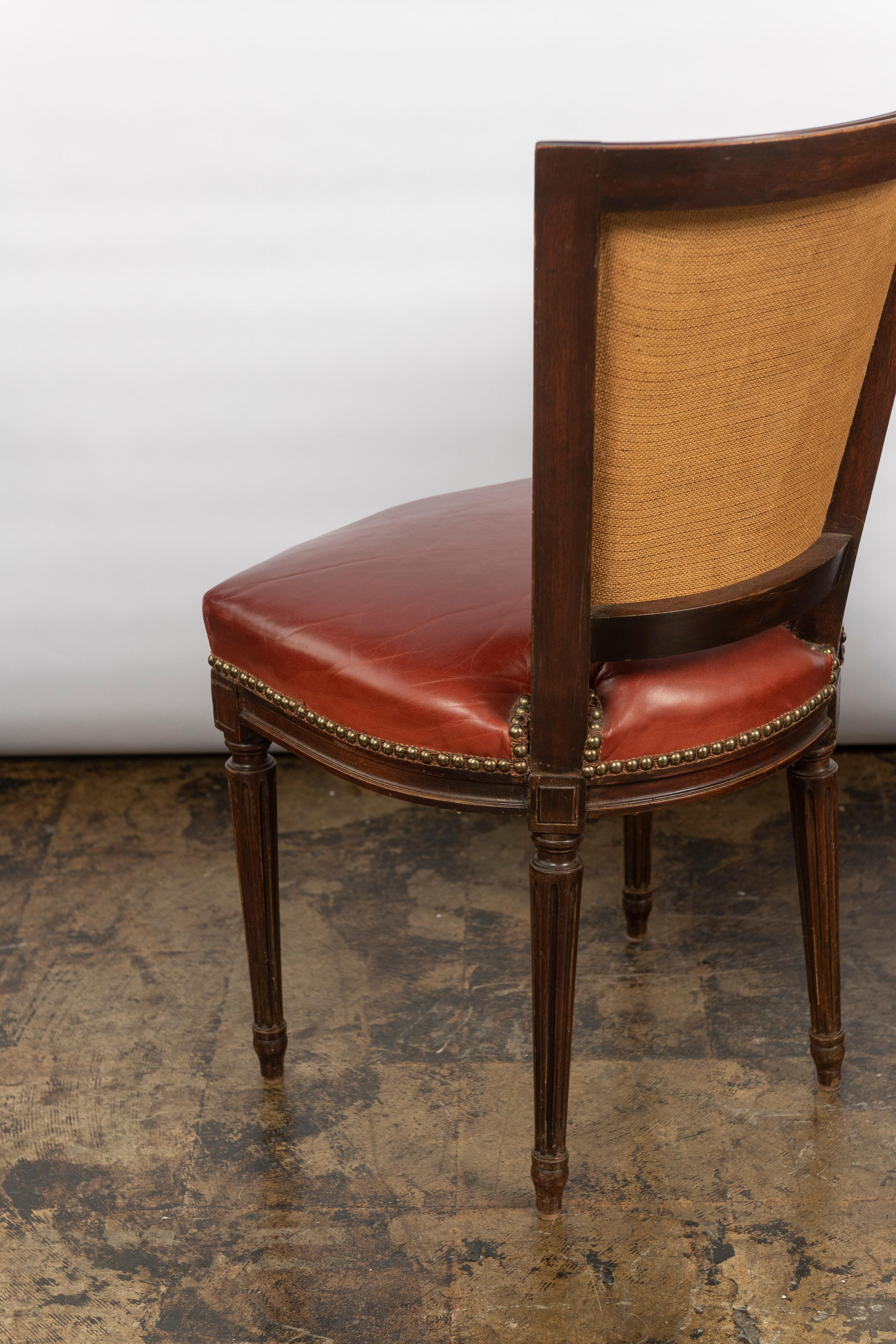 This vintage set of four French Louis XVI dining chairs have the original wood finish and upholstered in leather with brass nailhead detail. The frames of the dining/side chairs are tight without wobbling and chairs have a beautiful patina. Could