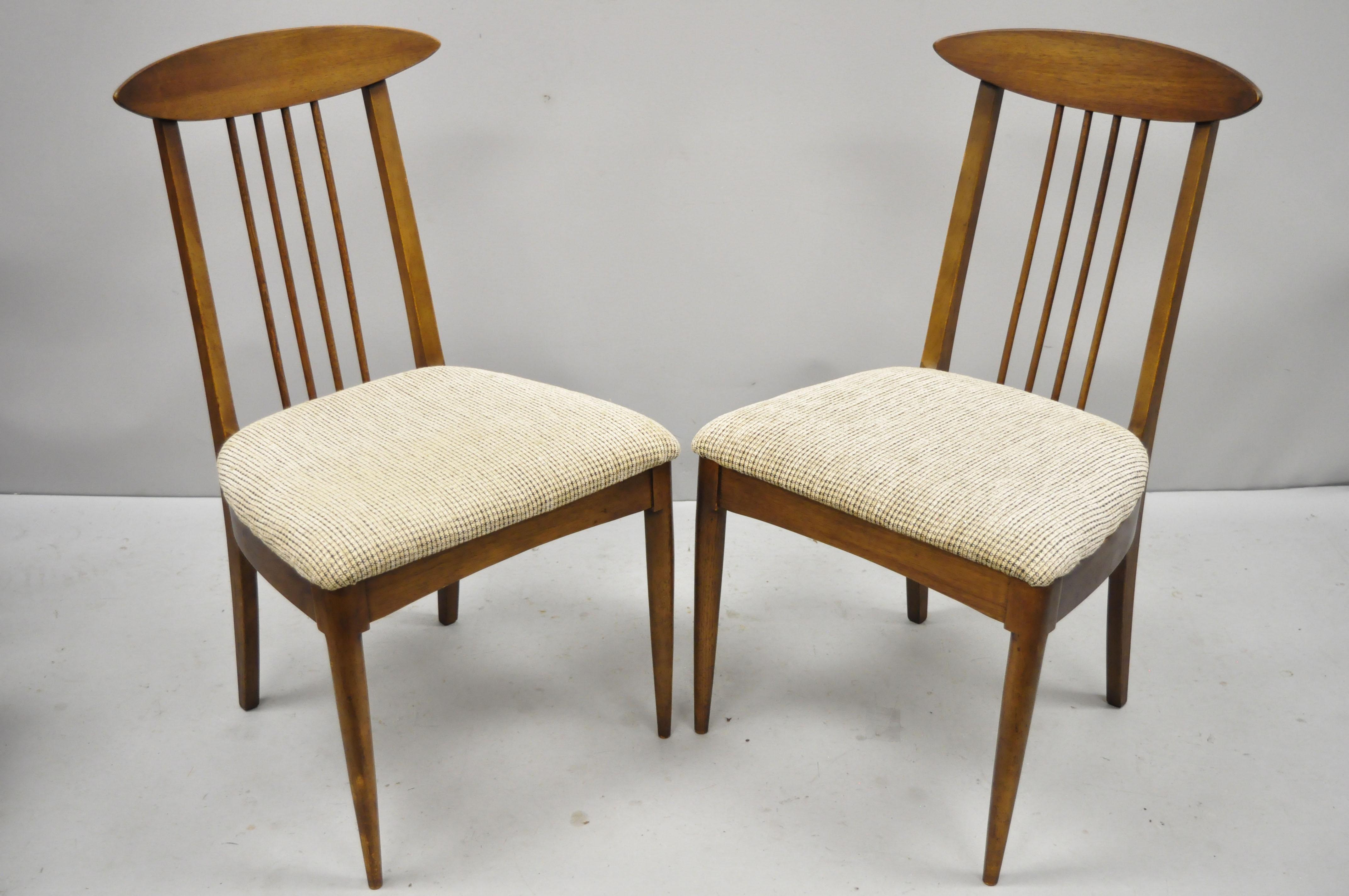 Set of four vintage Mid-Century Modern walnut spindle back dining chairs. Items feature spindle backs, curved rails, solid wood construction, beautiful wood grain, tapered legs, clean modernist lines, sleek sculptural form, circa mid-20th century.