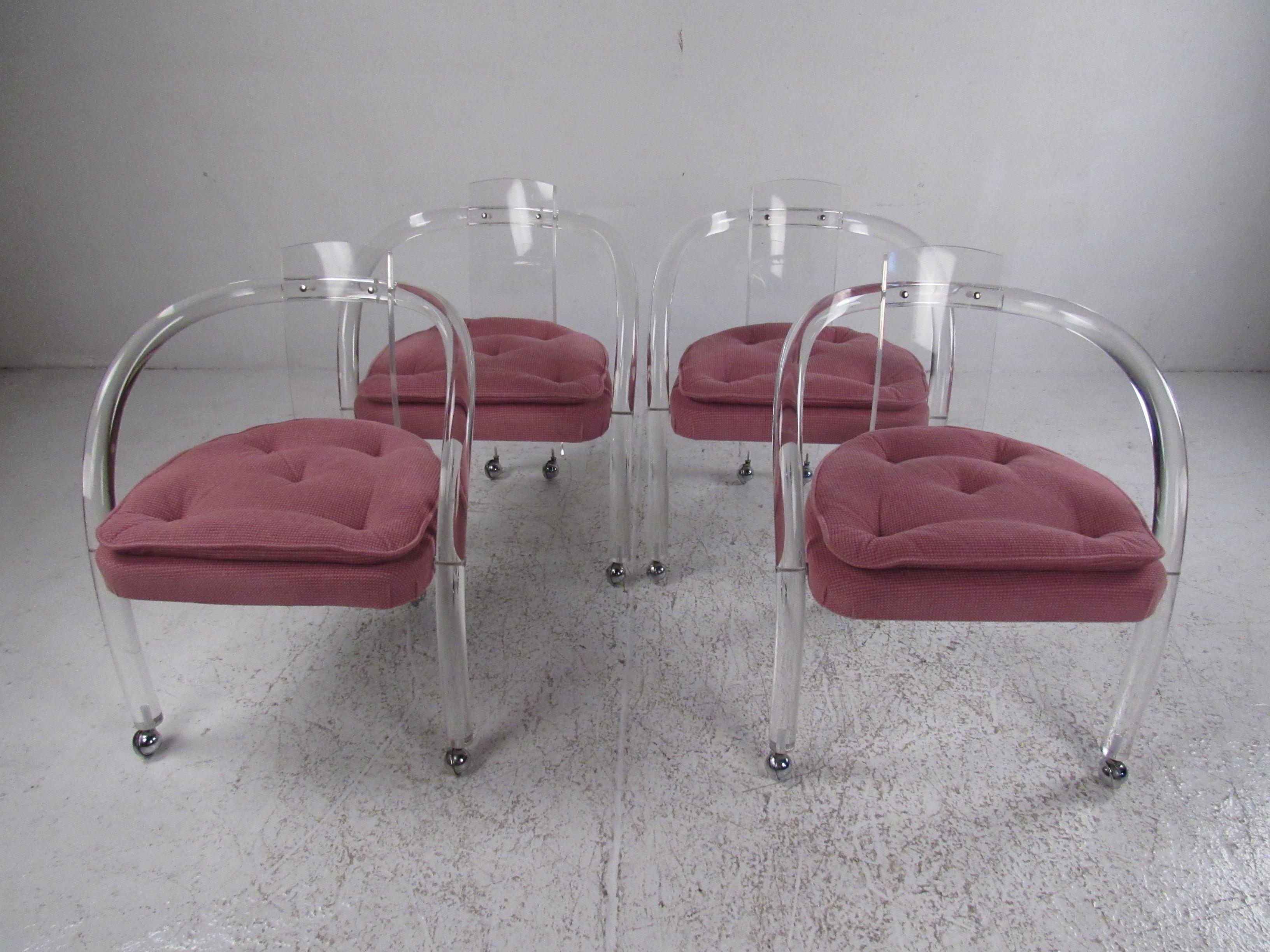 This stunning set of four Mid-Century Modern dining chairs boast a cylindrical Lucite frame with arched arm rests and a curved backrest. The thick padded seat is covered in a tufted purple fabric. A stylish and convenient design with castors on
