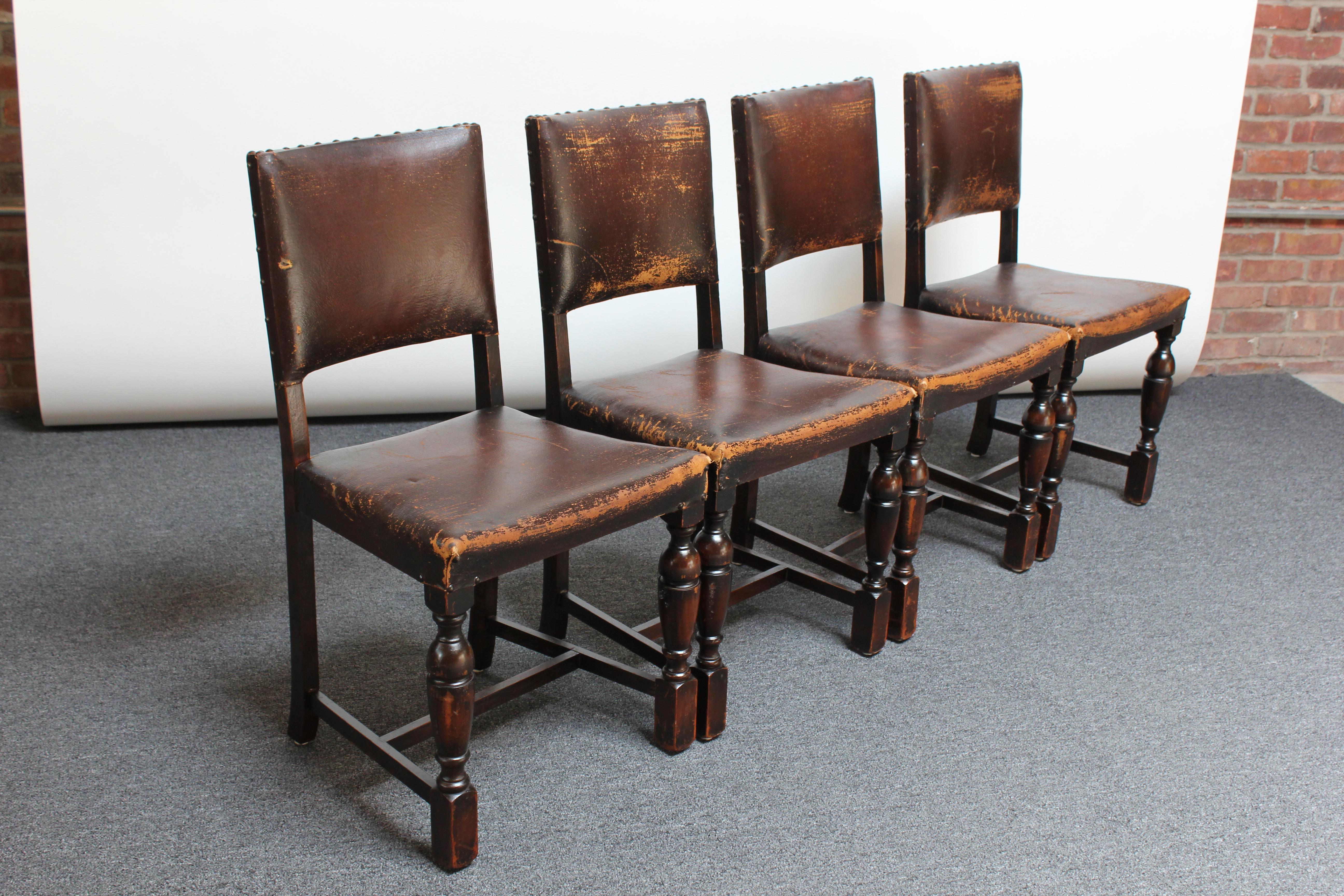 Set of four Spanish Revival hacienda dining or accent chairs (ca. 1930s, Spain). Features leather back and seat rests with mahogany frames and nailhead / stud detail. 
Warm patina / signs of use (scuffs / corner losses to the leather along with one