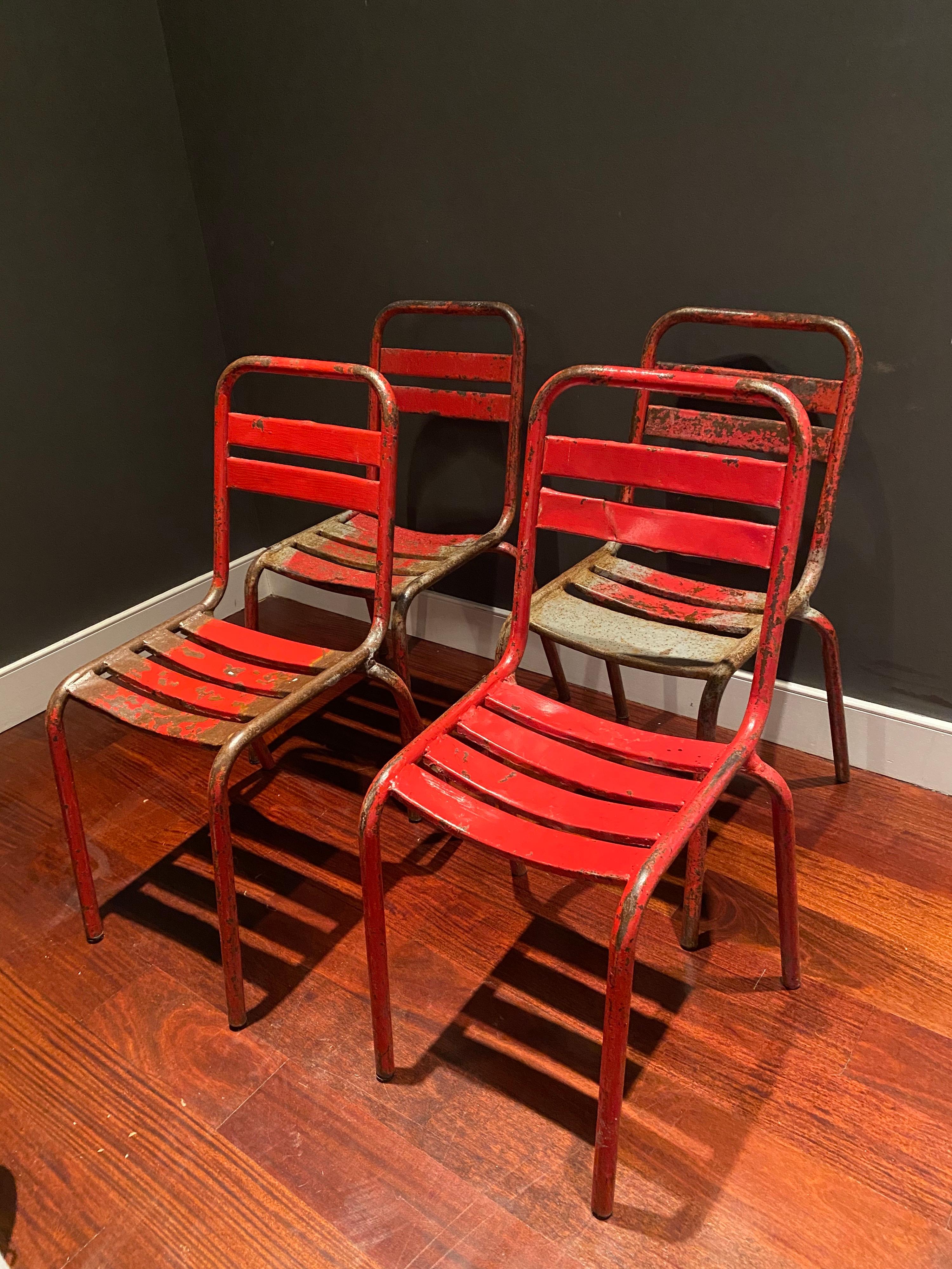 A set of four original Tolix bistro café chairs designed by Xavier Pauchard. Wonderful patina and red paint to each.