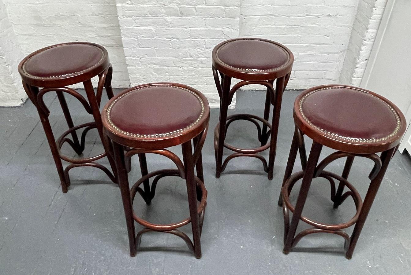 Set of four Thonet style bentwood stools. The stools have original vinyl seats with brass tacks. The frames of the stools are beech and are bentwood.