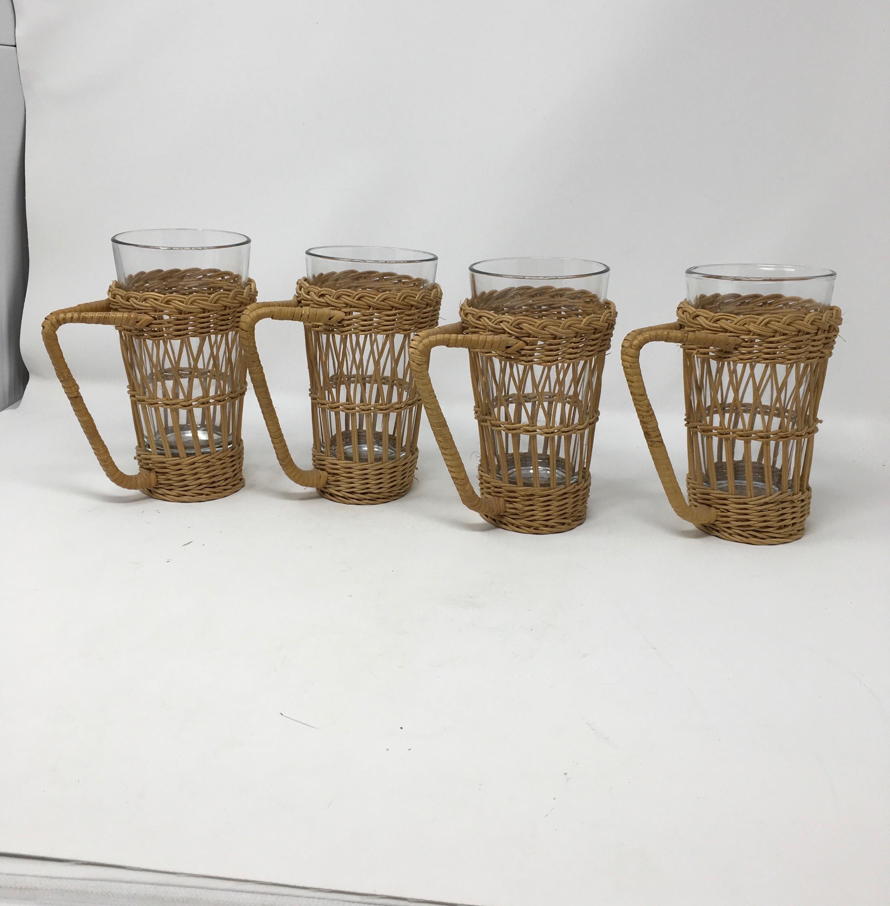 This set of four vintage Wicker rattan glass holders includes four removable glass tumblers. Each holder is intact with sturdy handles to hold both hot and cold beverages.