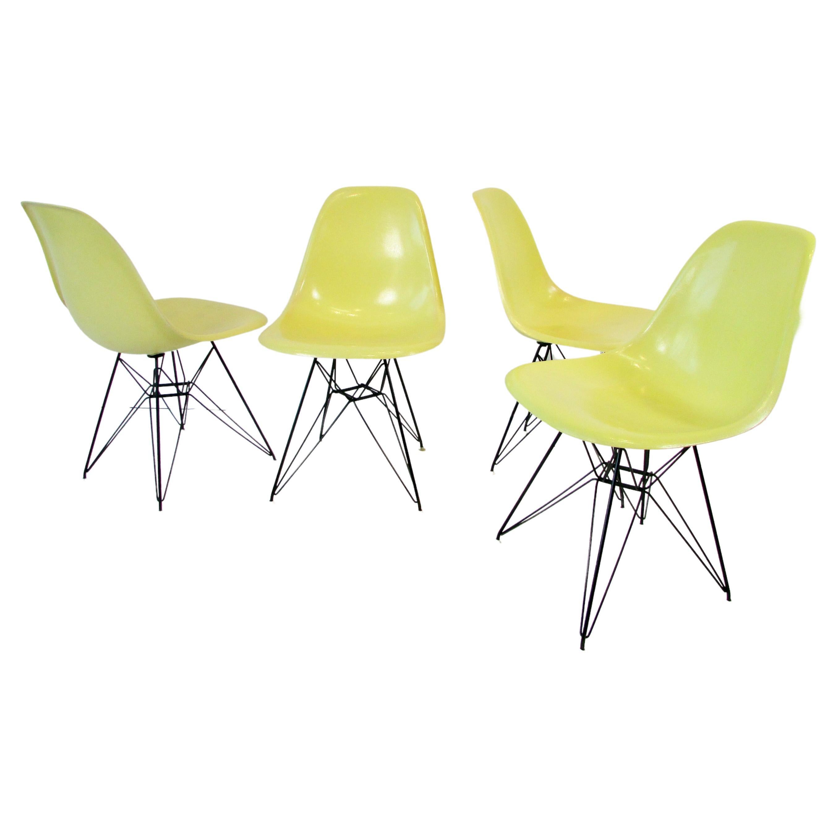 Ensemble de quatre chaises Eames DSR en fibre de verre jaune vif sur socle Tour Eiffel noir