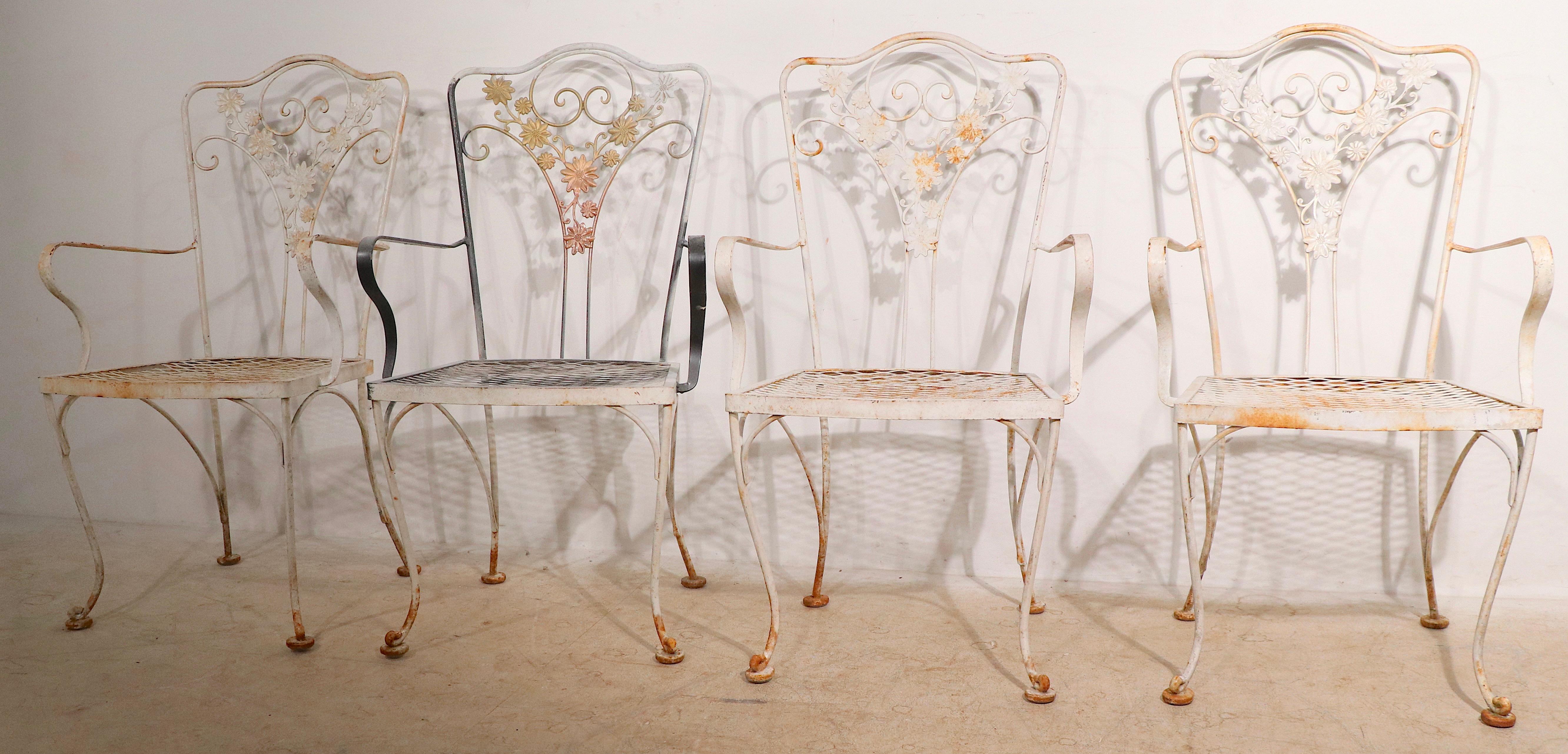 Set of four Woodard Orleans pattern dining arm chairs. The chairs are structurally sound and sturdy, the paint finish shows wear and variations throughout. Unusual to find four matching arm chairs. Usable as is or we offer custom powder coating if