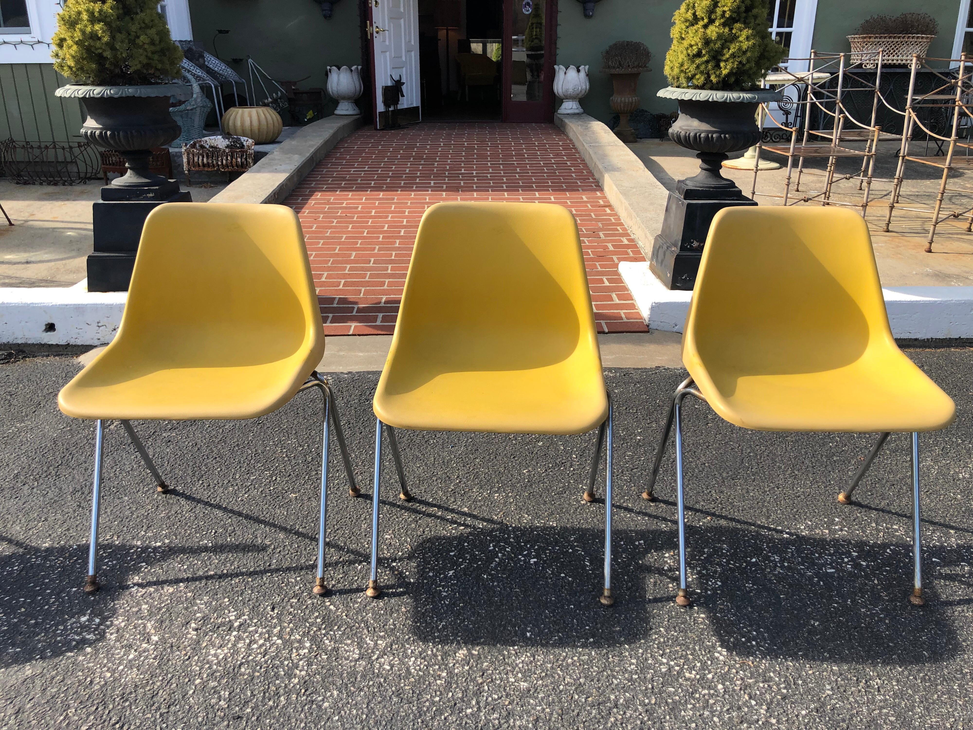 Set of three yellow Jon Stewart Stackable shell chairs. Plastic composition with metal lag base. Signed on underside of plastic seat. Fourth chair is faded more than the others so will include at no cost. Rust to metal base and legs. Plastic roller