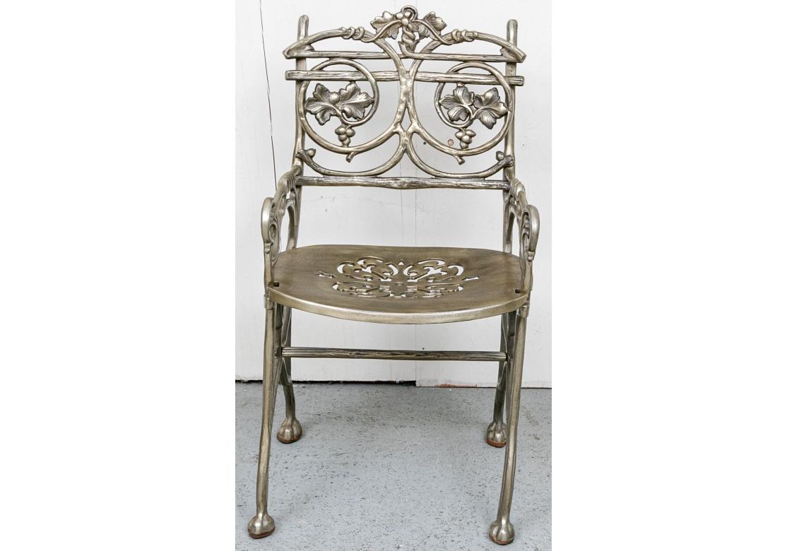 Un ensemble de quatre chaises de jardin en fonte d'aluminium, bien fabriquées et confortables, dont la décoration comprend des vignes, des grappes de raisin, des torsades et des accents en faux bois. Les sièges sont percés pour le drainage et ont