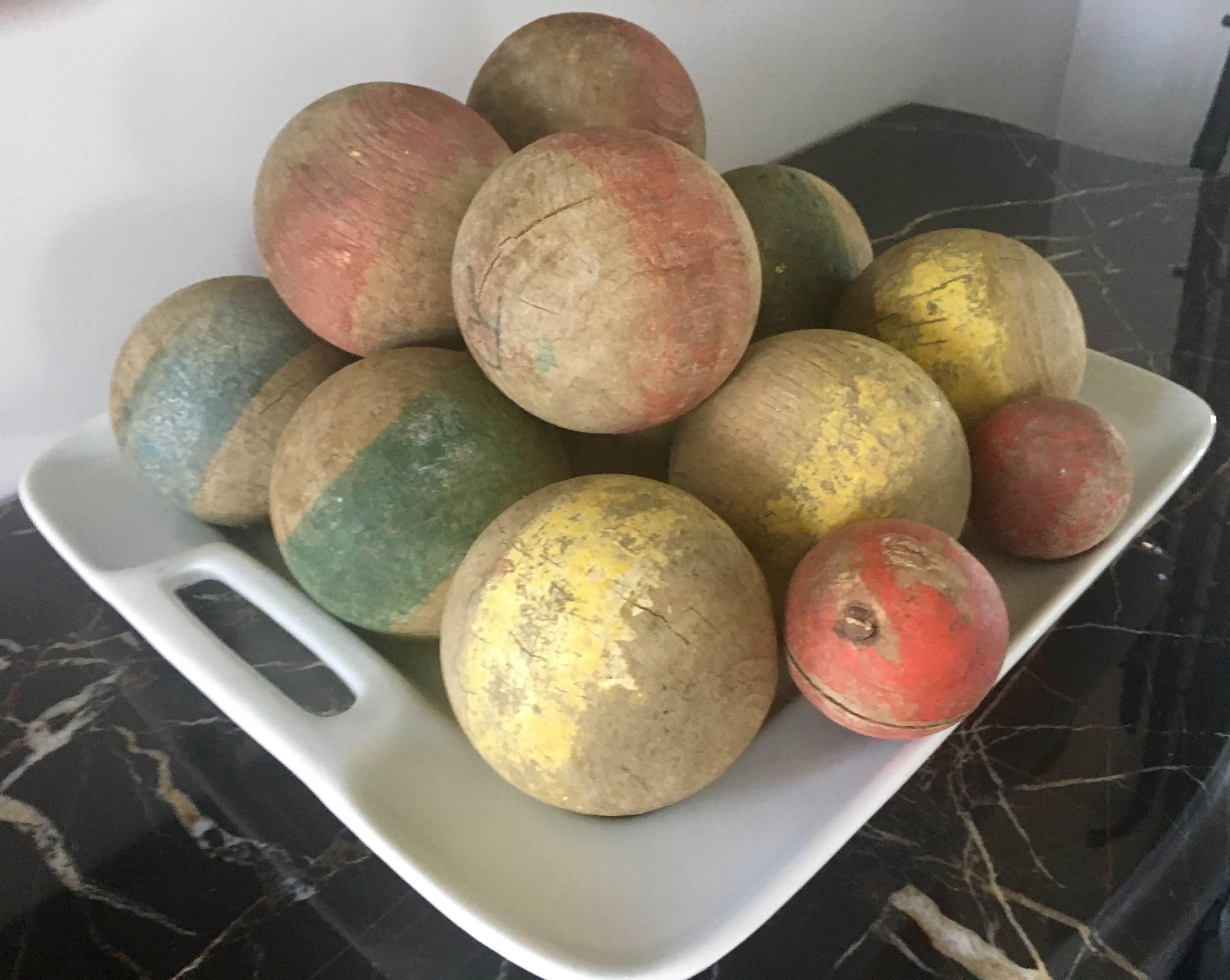 Dating to the late 19th century, this wonderful set of hand-carved French boules comprises twelve large balls, each with worn and original painted stripes in yellow, red, blue and green, and the two smaller accompanying target balls, both in red. We