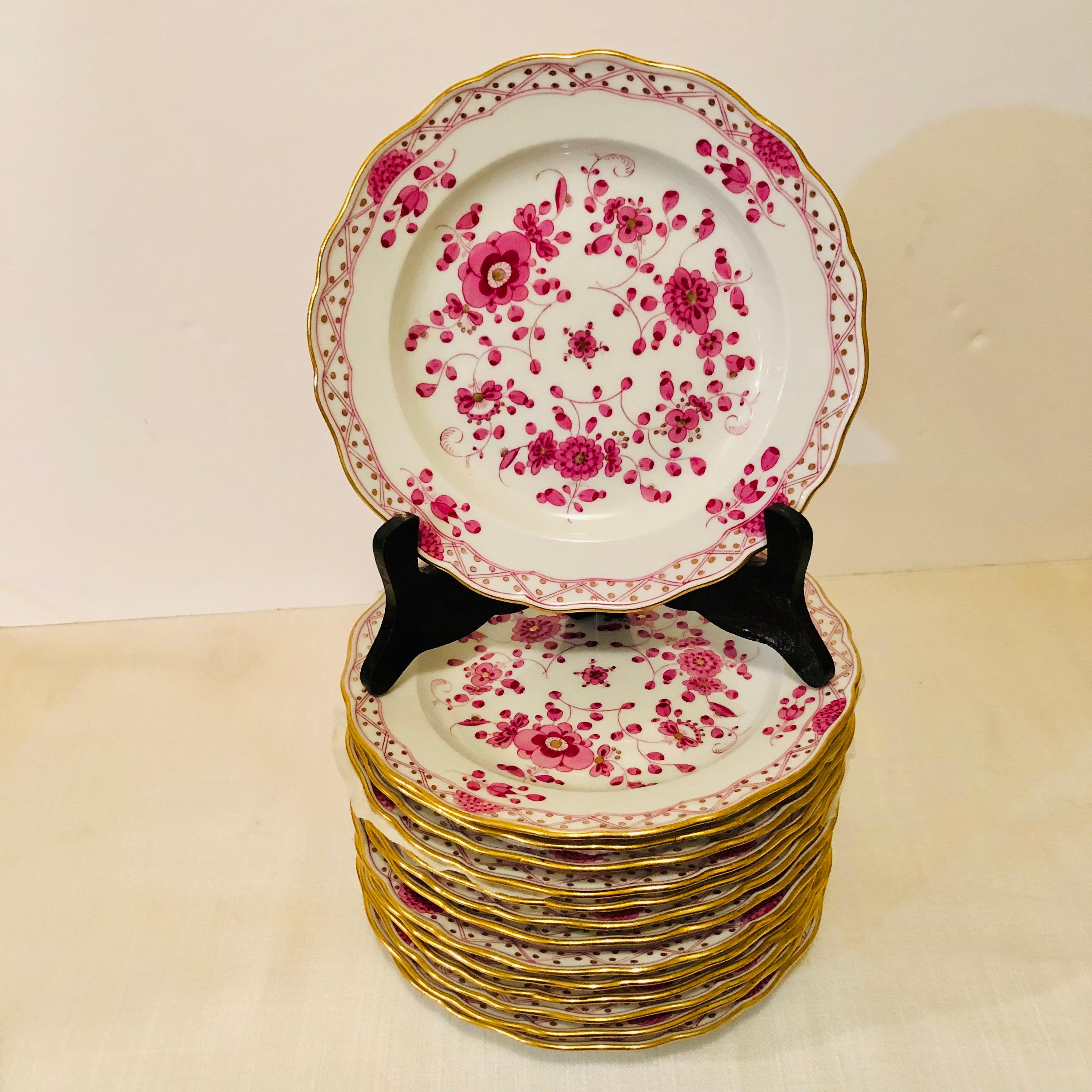 This is an exquisite set of fourteen Meissen purple Indian pattern dessert plates from the 1890s. It has detailed paintings of pink flowers with some purple and gold accents on a white ground. The detail of the painting on these dessert plates is