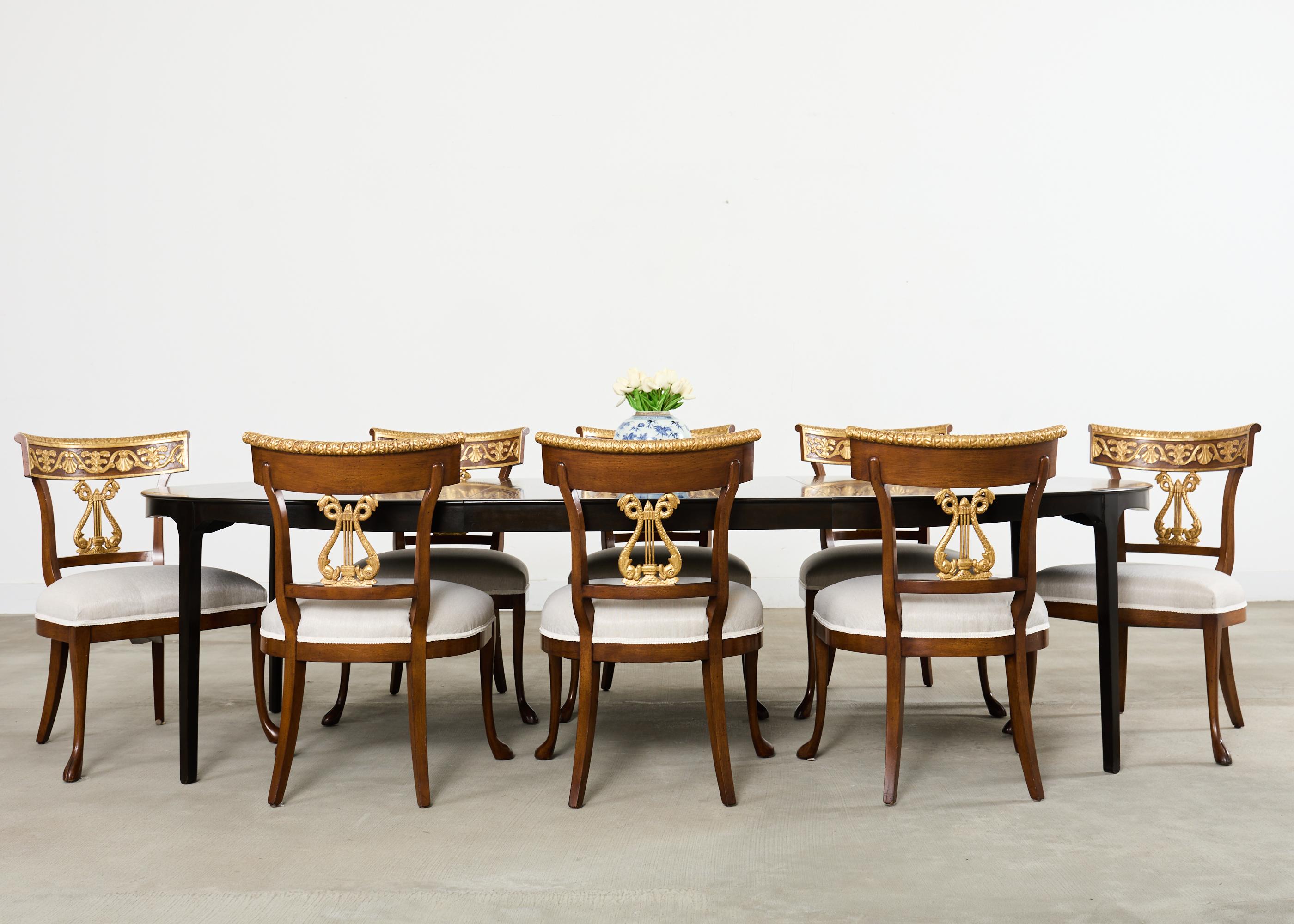 Remarkable grand set of fourteen neoclassical style dining chairs designed by Nancy Corzine in the California romantic style. The chairs feature a walnut frame with a klismos style tablet back decorated with 22k gold. The back splat has a dramatic