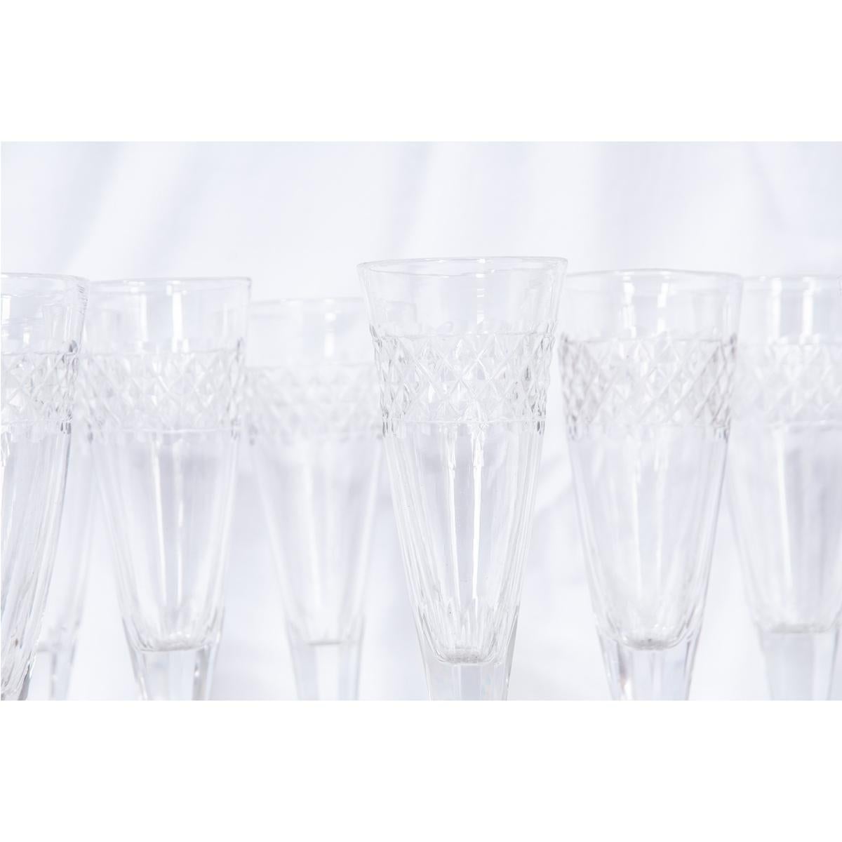 Set of 13 French glasses, circa 1820. These crystal flutes have a cut design around the bowl and overall tapered design with faceted stems.