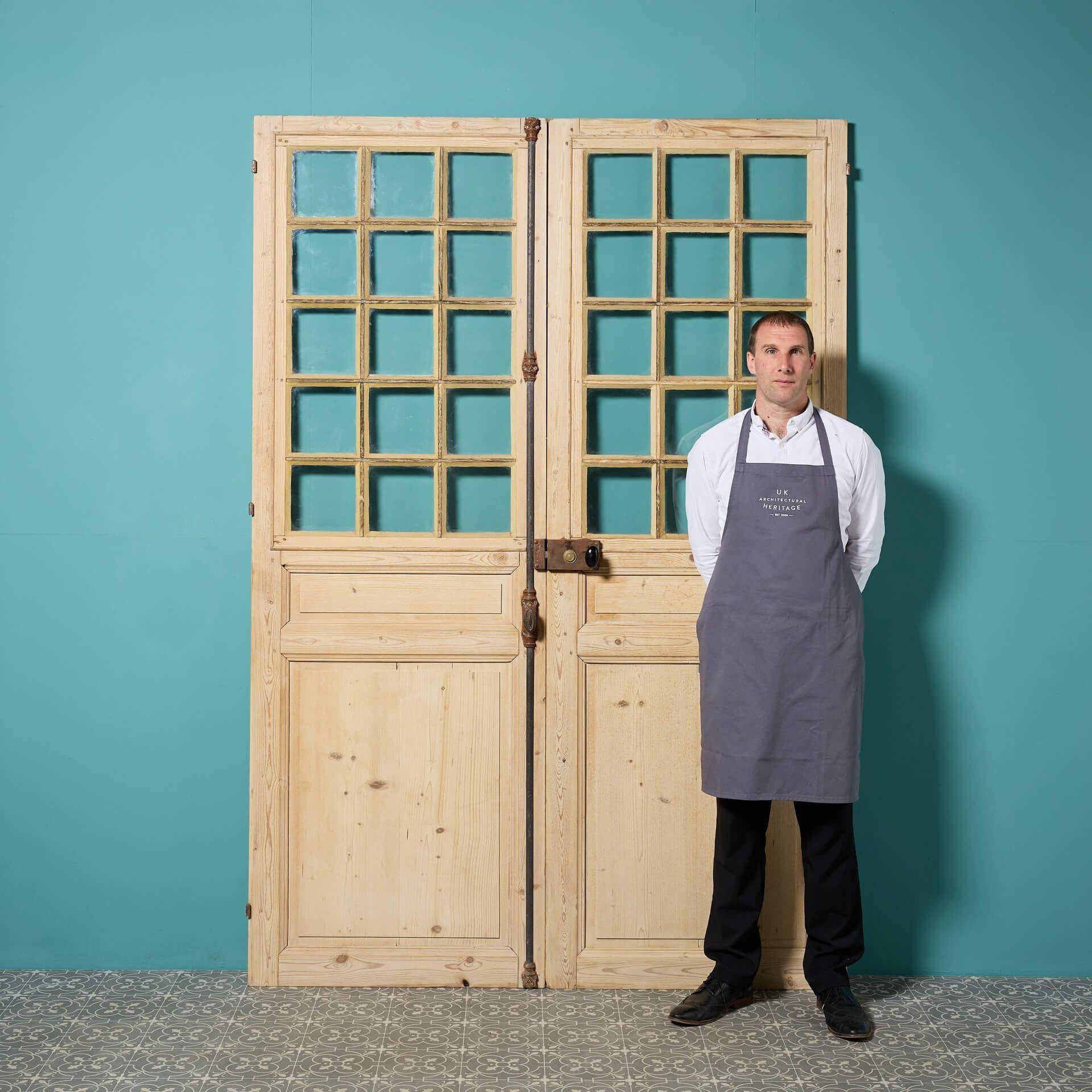 Una serie di porte doppie in pino antico provenienti dalla Francia, la metà inferiore con pannelli in rilievo e campiture e la metà superiore con vetri singoli trasparenti. Adatte all'uso interno, queste porte doppie recuperate saranno un'ottima