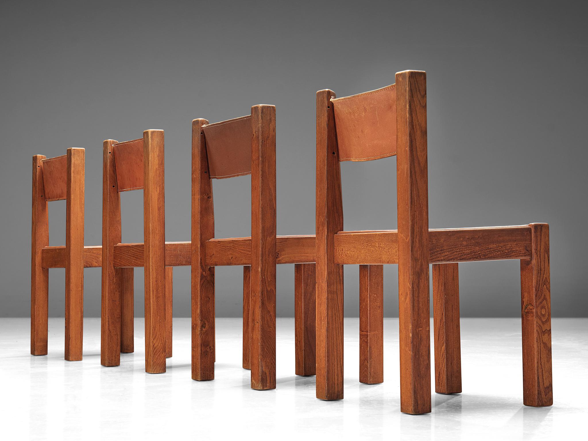 Set of four dining chairs, oak and cognac leather, France, 1960. 

A set of four chairs in solid oak with cognac saddle leather seating and back. These chairs have a geometric design that is strong in its simplicity. The color of the cognac leather