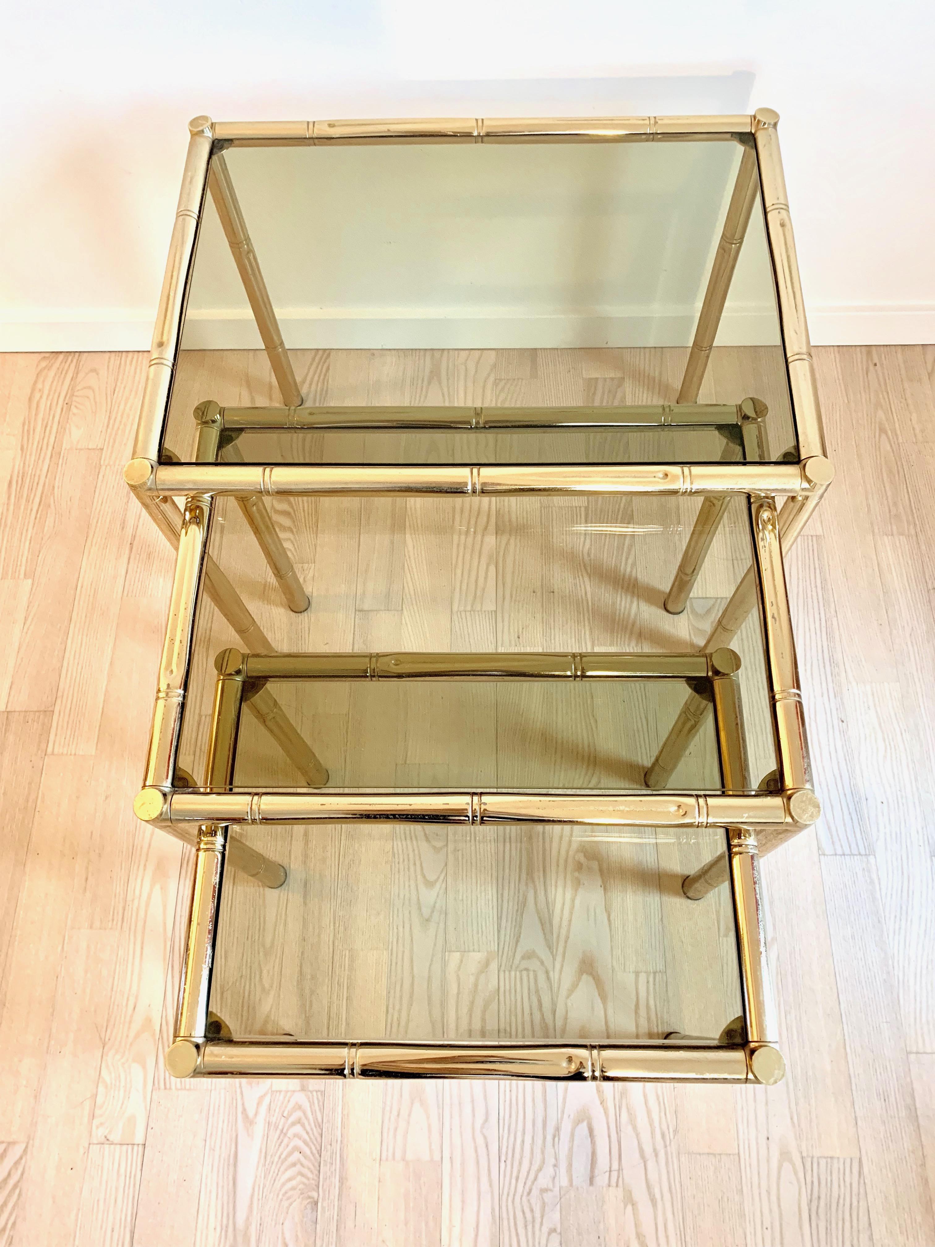 Brass French nesting tables with smoked glass tops. In the style of Maison Baguès.
 