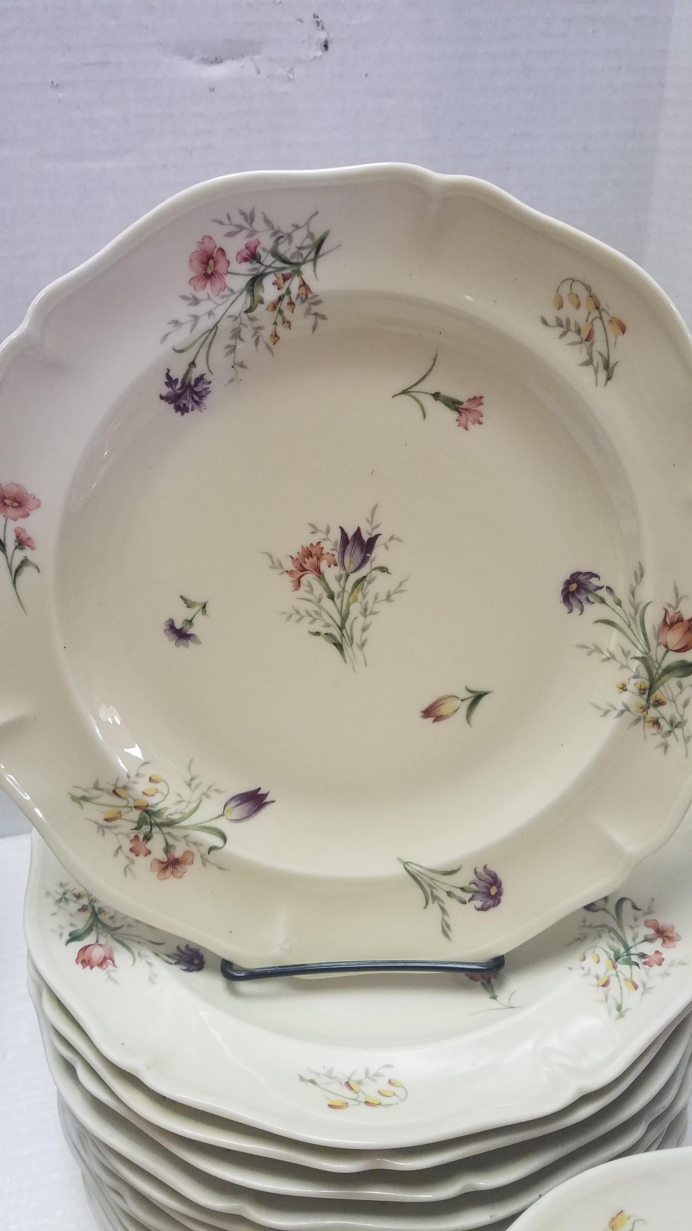 Set of vintage French Limoges dinnerware. See Makers Marks on the back of the pieces. Purchased from the Brittany region of France. Beautifully hand painted with scattered flowers in shades of pink yellow and purple with green foliage. The set