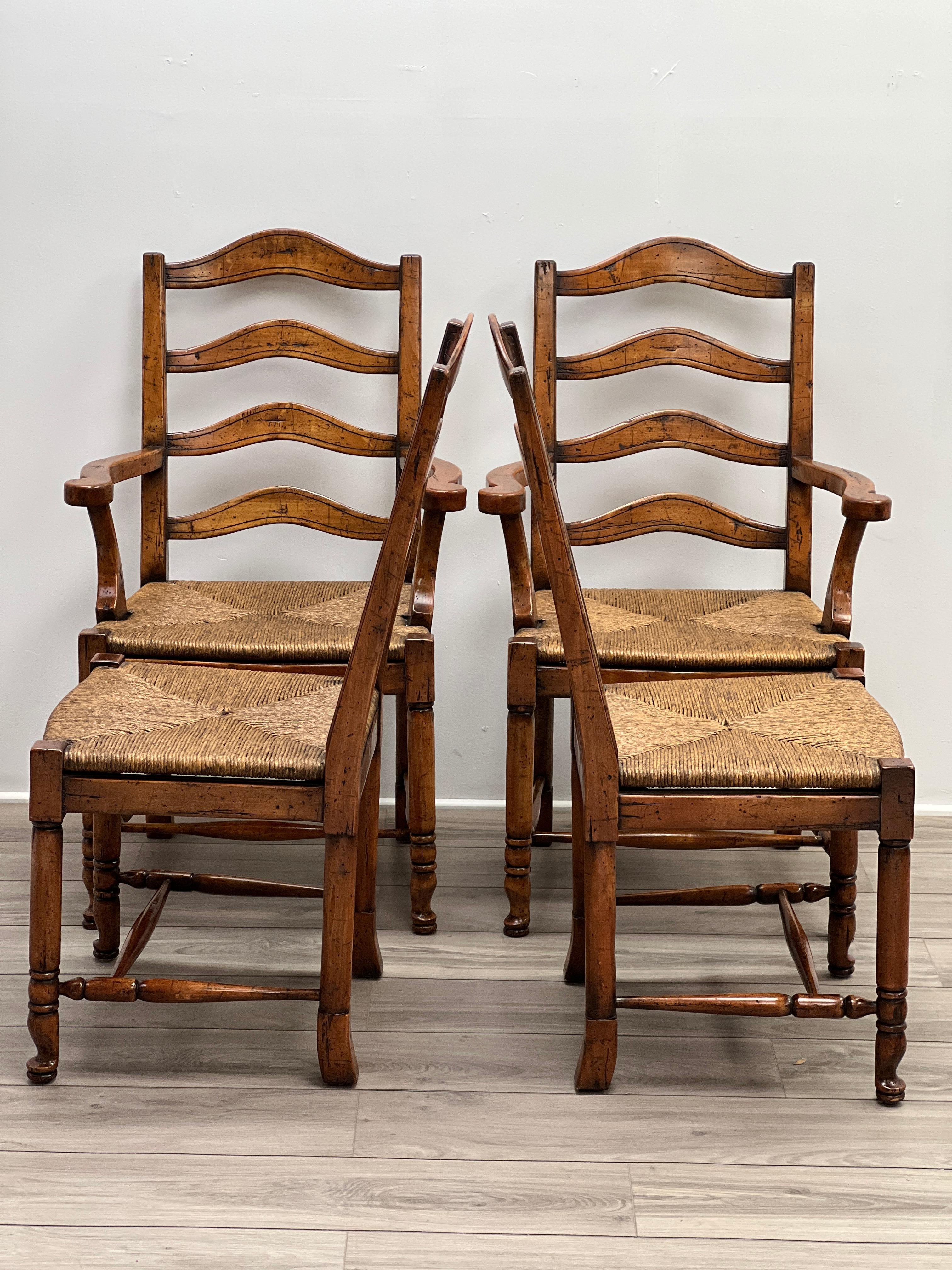 Featured is a gorgeous set of four of French Provincial style ladder back dining or kitchen chairs with hand-woven rush seating. The front legs are turned and connects ted to the rear legs with turned leg stretchers. The center is supported with a