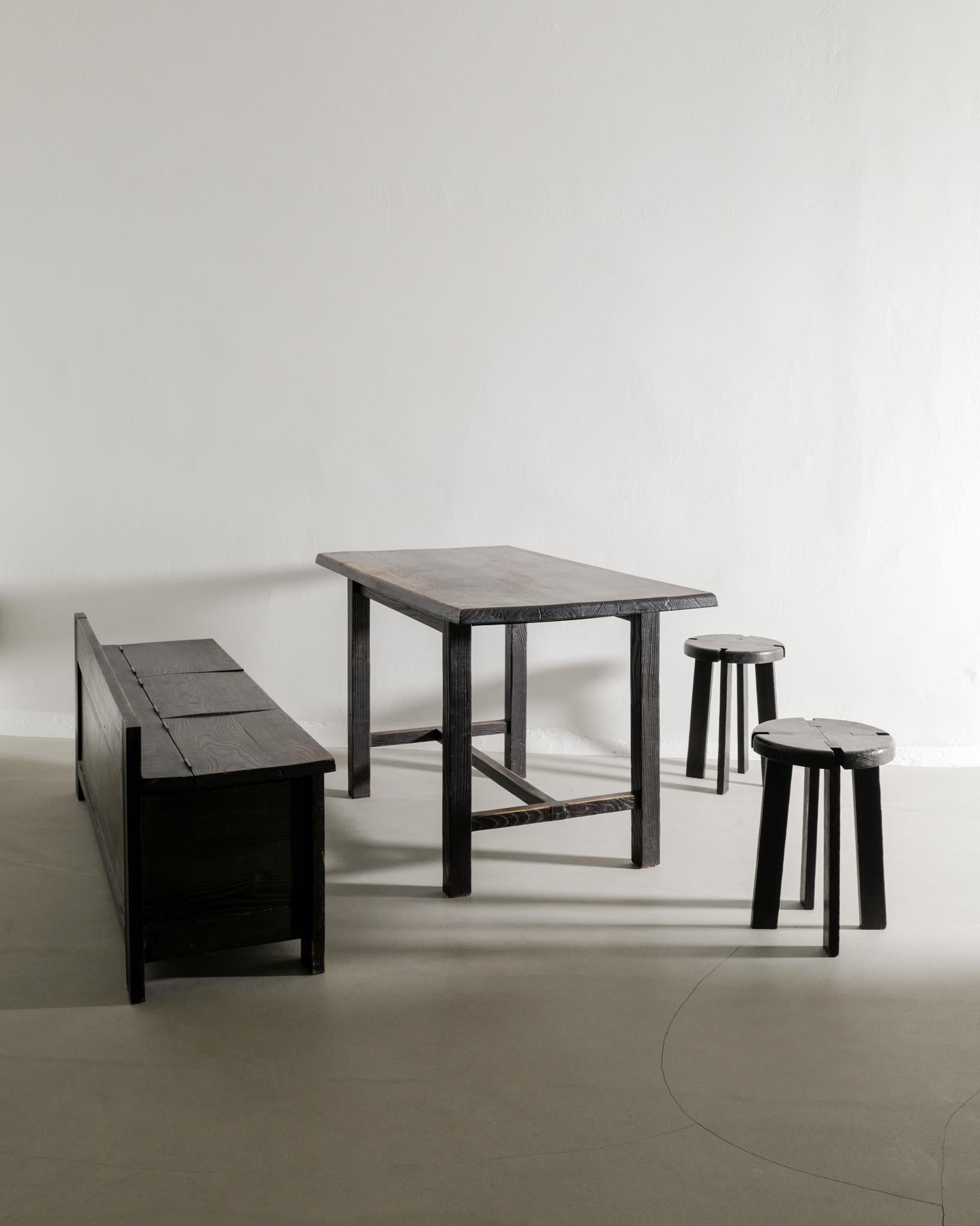 Rare ensemble de salle à manger en bois du milieu du siècle en chêne teinté foncé dans un style rustique par un designer anonyme français produit dans les années 1950. Le canapé dispose d'un espace de rangement sous les sièges et les tabourets à