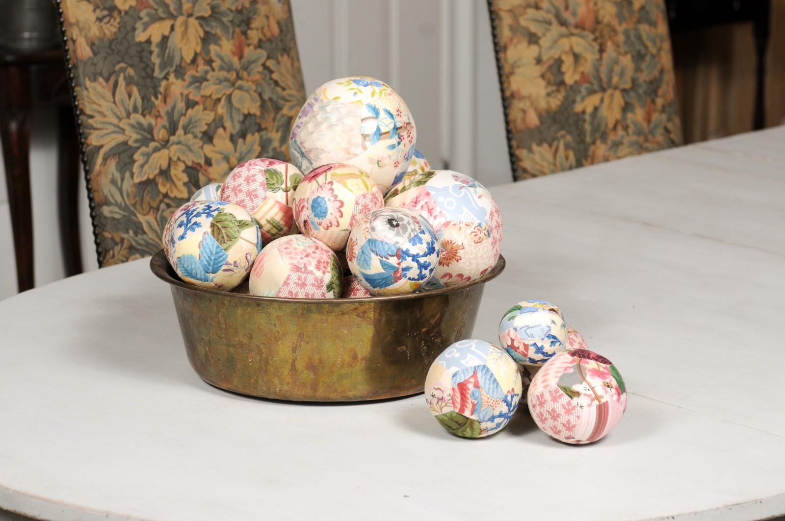 A set of unique French vintage cloth balls from the 20th century displayed in an antique circular brass bowl. Created in France during the 20th century, this set of cloth balls charms us with its colorful décor and variety of sizes. Ranging from 3