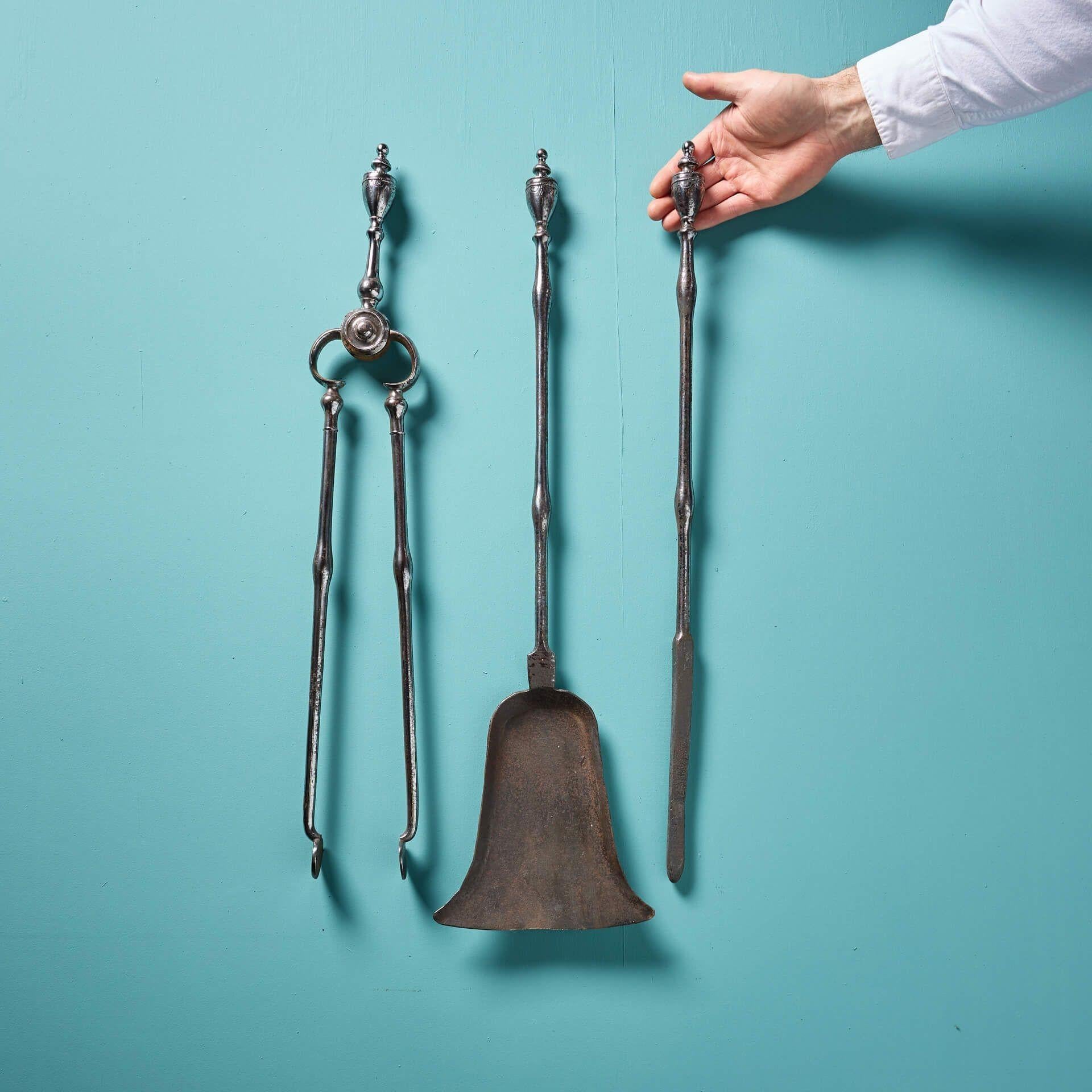 Un set di tre ferri da stiro originali di alta qualità di Giorgio III.
Questo set di attrezzi per il fuoco comprende un attizzatoio, una pinza e una pala con decorazioni incise e pomelli a forma di urna sui manici. Il tocco finale perfetto per