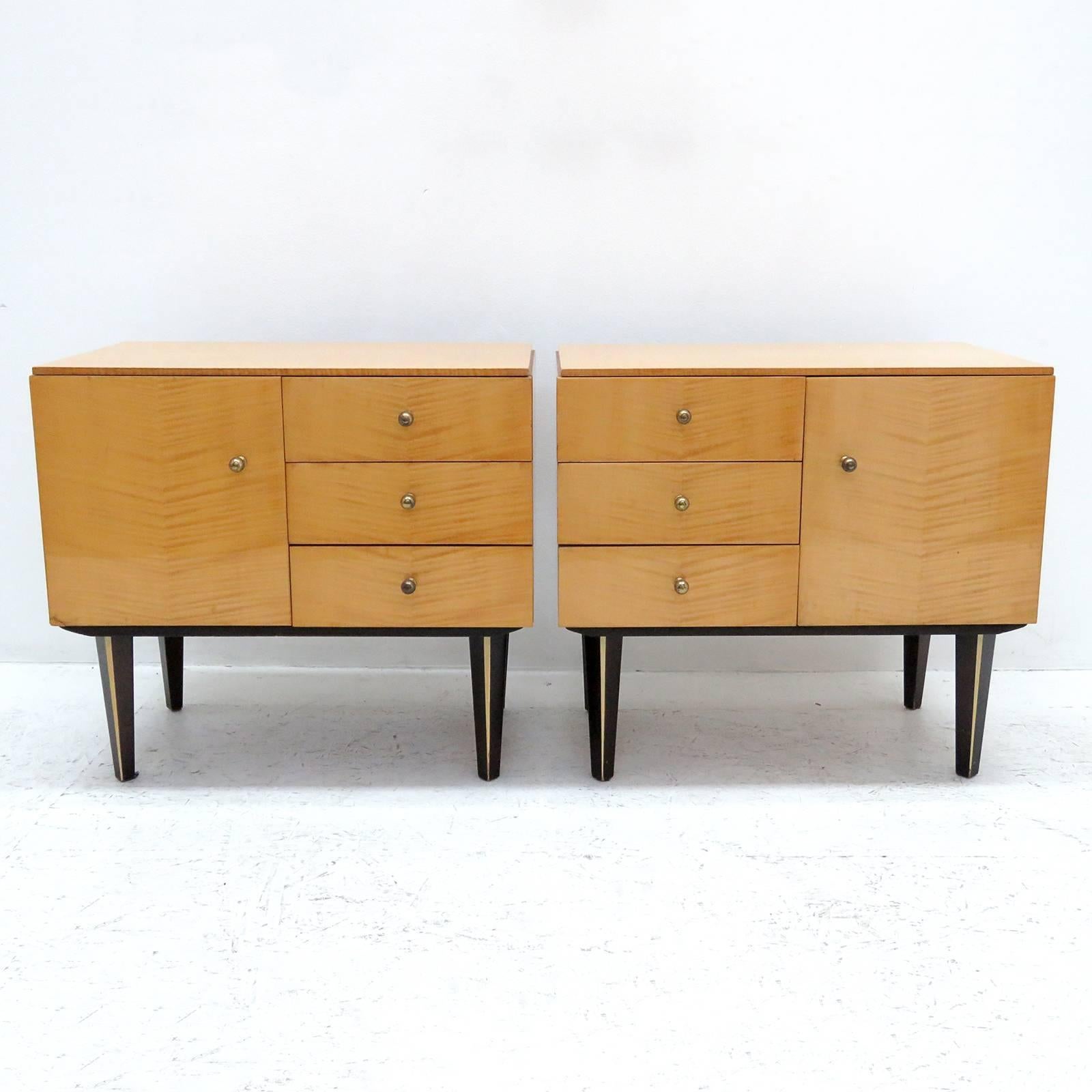 wonderful set of 1950s German birch veneer nightstands with one door and three drawers each, brass hardware, legs painted black with a decorative egg shell colored vertical strip.
 