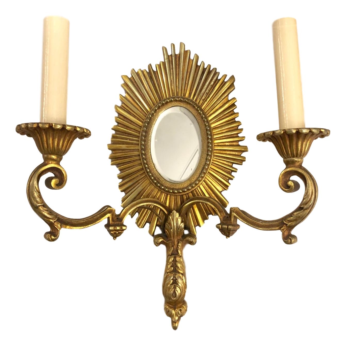 Set of four circa 1940s French two-arm gilt bronze sunburst shaped sconces with mirror insets on backplate. Sold in pairs.

Measurements:
Height 14