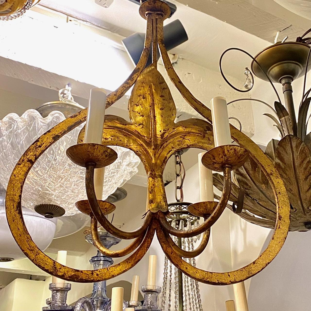 A set of three circa 1940's French gilt metal chandeliers with fleur-de-lys motif and four lights. Sold individually.

Measurements:
Height: 23.5