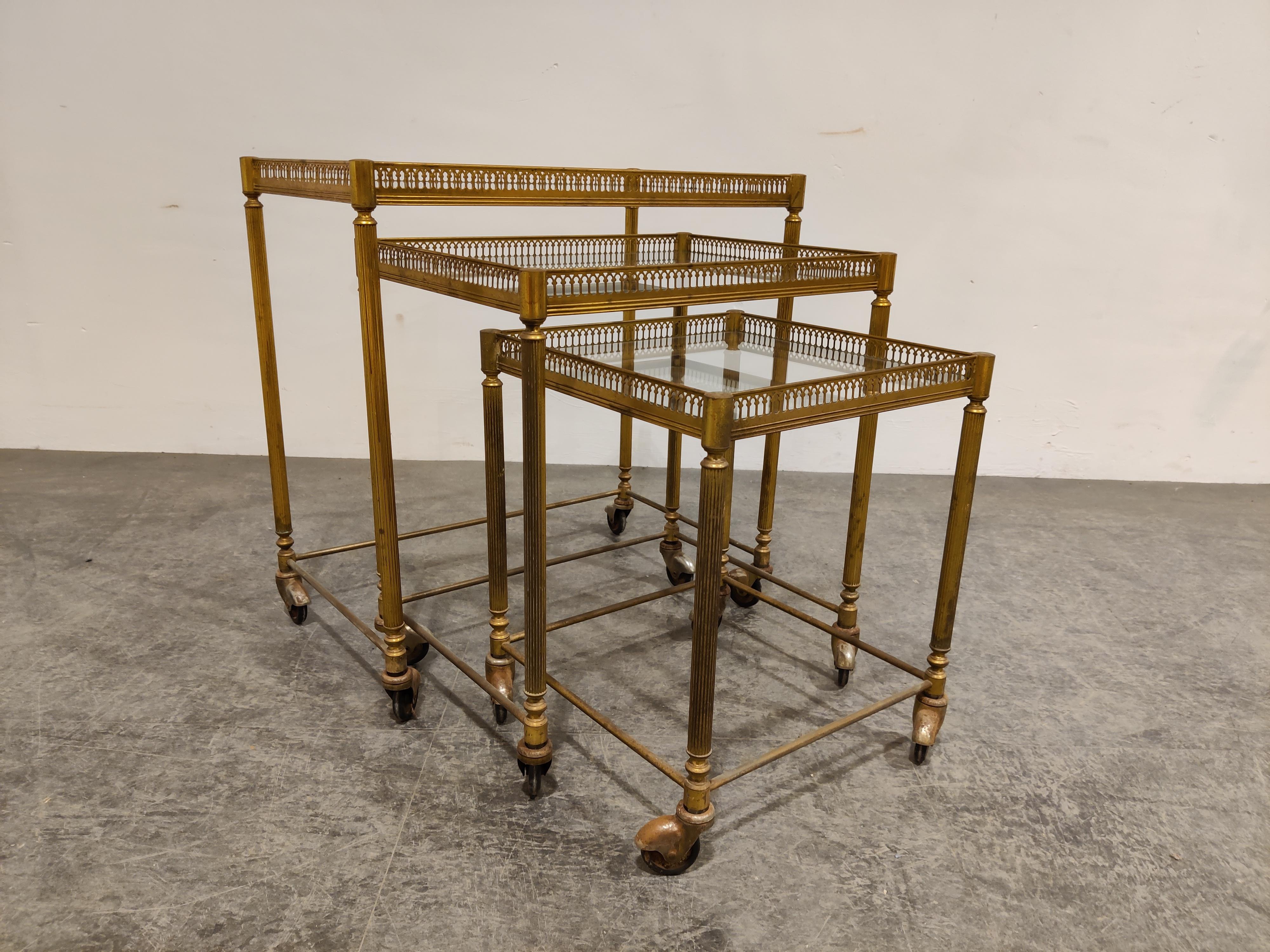 Very elegant set of patinated gilt metal neoclassical nesting tables on wheels in the style of maison Baguès.

The tables still have their original glass.

Wear and patina consisten with age.

1960s - France

Dimensions of the largest