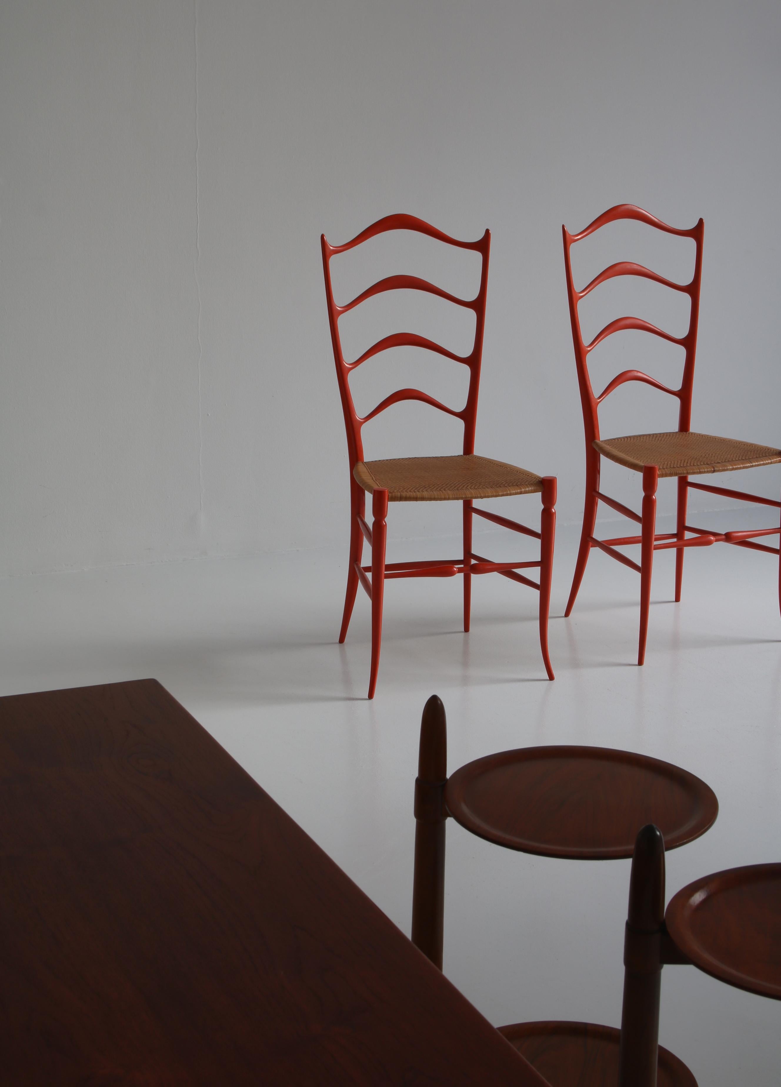 Stunning pair of Italian ladder back chairs made at A. Bulleri & Co. Cascina in the early 1950s and attributed to Gio Ponti. The chairs are made from red lacquered wood and delicate seats in finely woven rattan cane. The model is called 