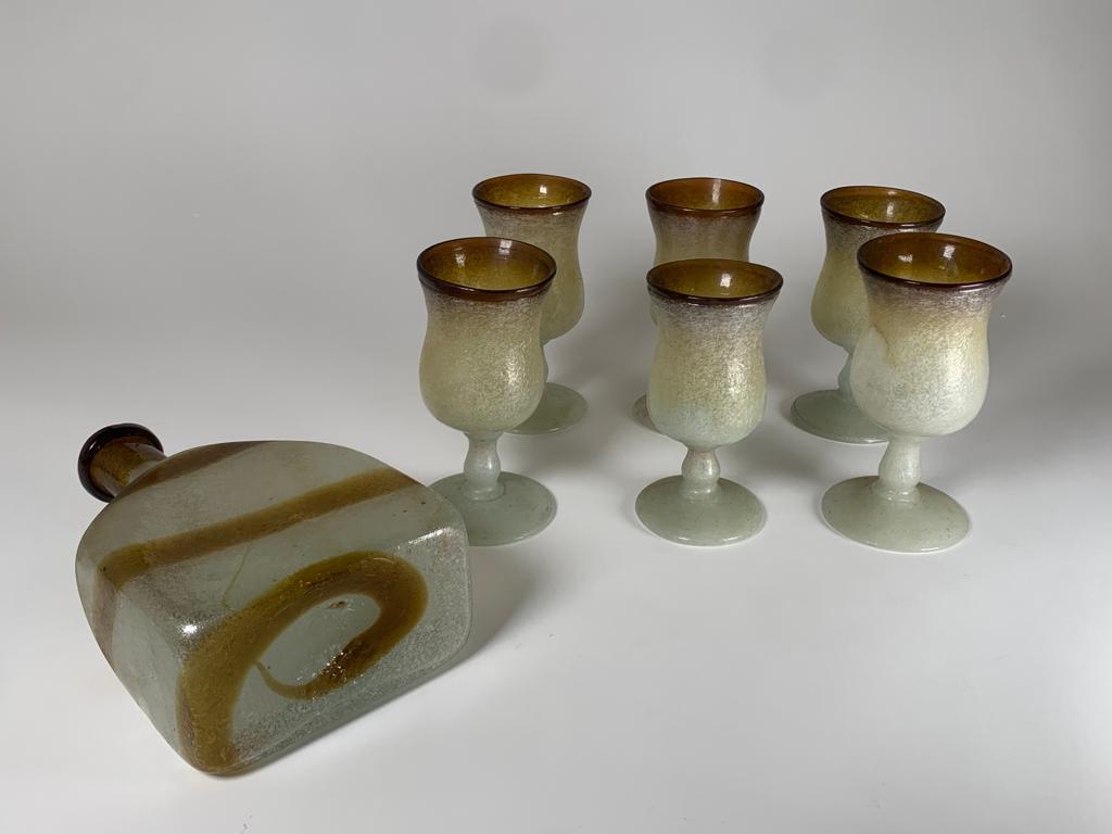 Set aus sechs Gläsern und einer Flasche aus Pulegoso-Glas, entworfen von Flavio Poli für Seguso Vetri d'Arte im Jahr 1940. Die Abmessungen der Flasche sind H 22 cm x B 14 cm x T 6 cm

Biografie
Designer, Geschäftsmann, Keramikkünstler. Er wurde in