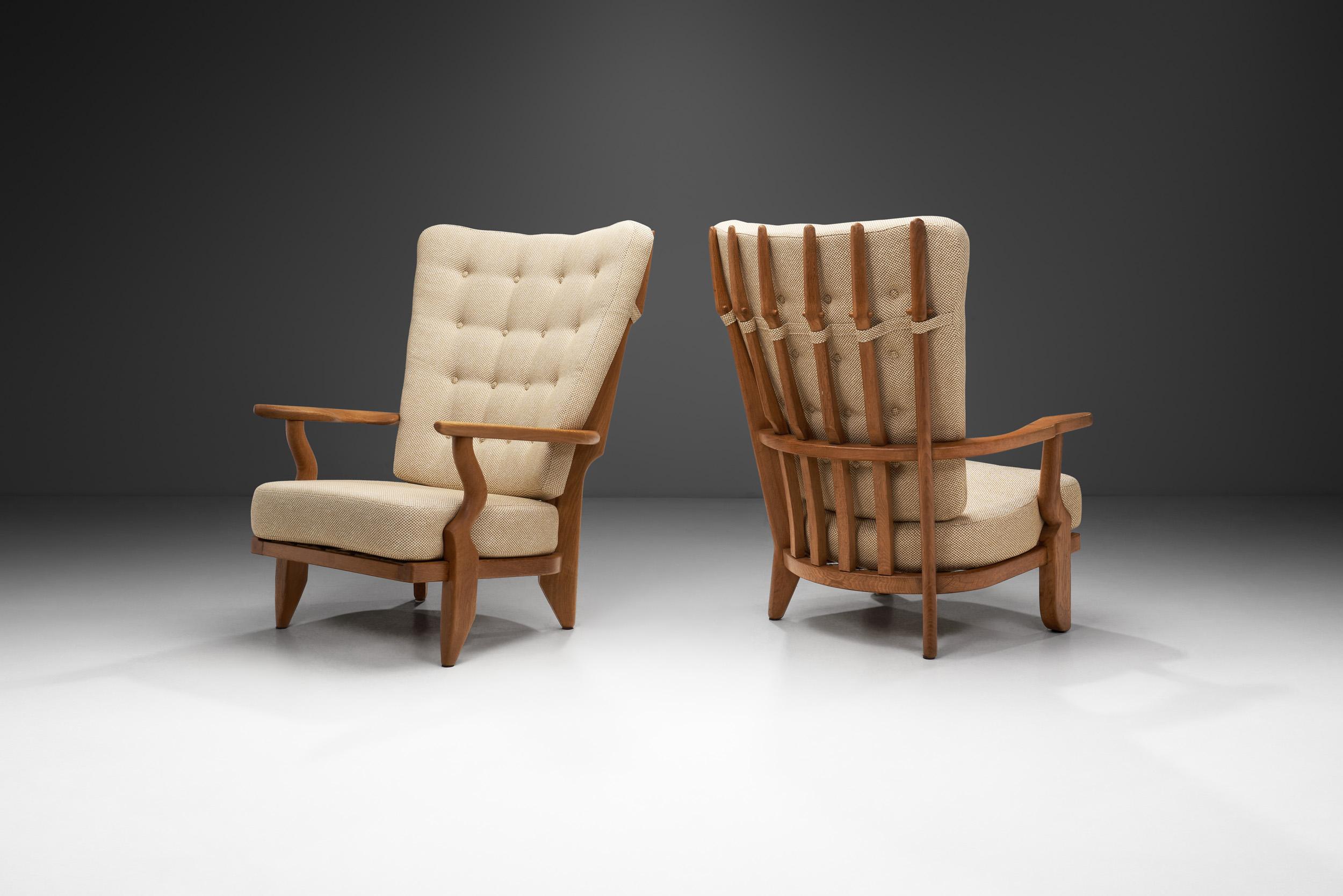 Ces chaises de salon 'Grand Repos' de Guillerme et Chambron présentent un beau contraste entre la structure en chêne clair et l'élégant tissu clair des coussins. Avec un cadre en bois massif, le support du dossier est constitué de six fuseaux en