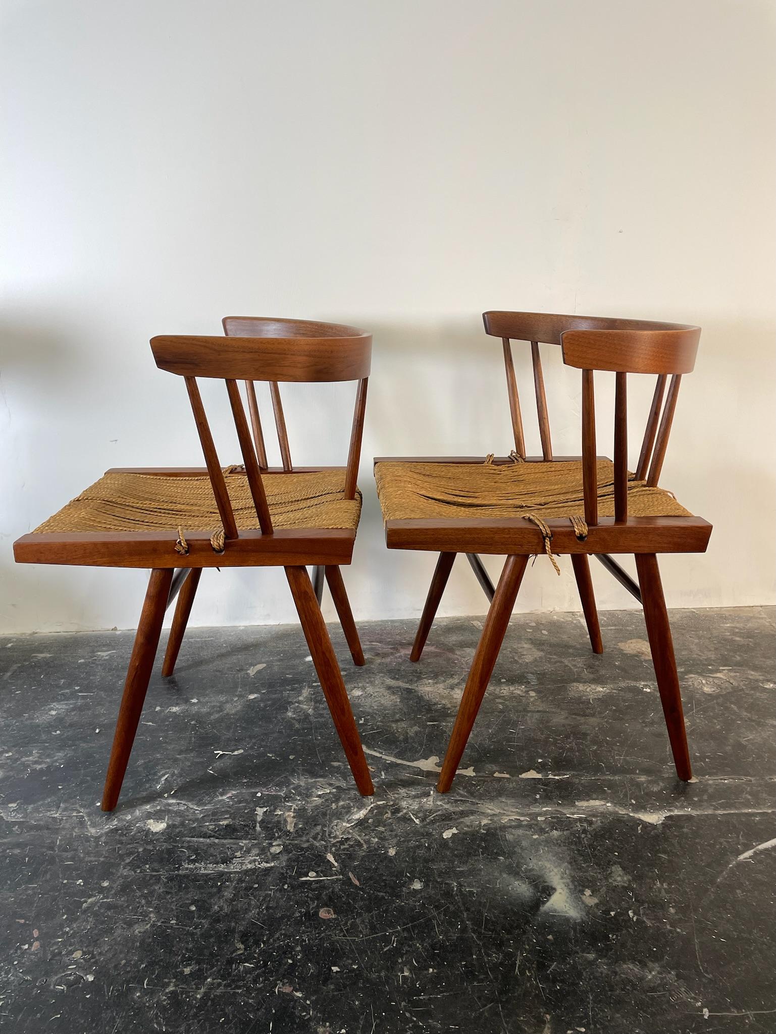 Grass-seated circa 1960s production in black walnut by George Nakashima with original seagrass seats. Also priced individually in other listings. Price is for the two chairs and stool. These were purchased from the family who owned them originally.