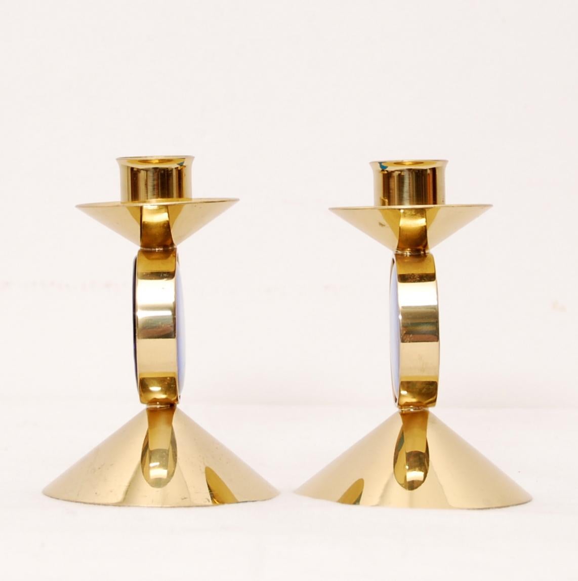 A set of two Gunnar Ander candleholders in brass with mounted blue art-glass. Manufactured by Ystad Metall. Stamped and signed.
   
