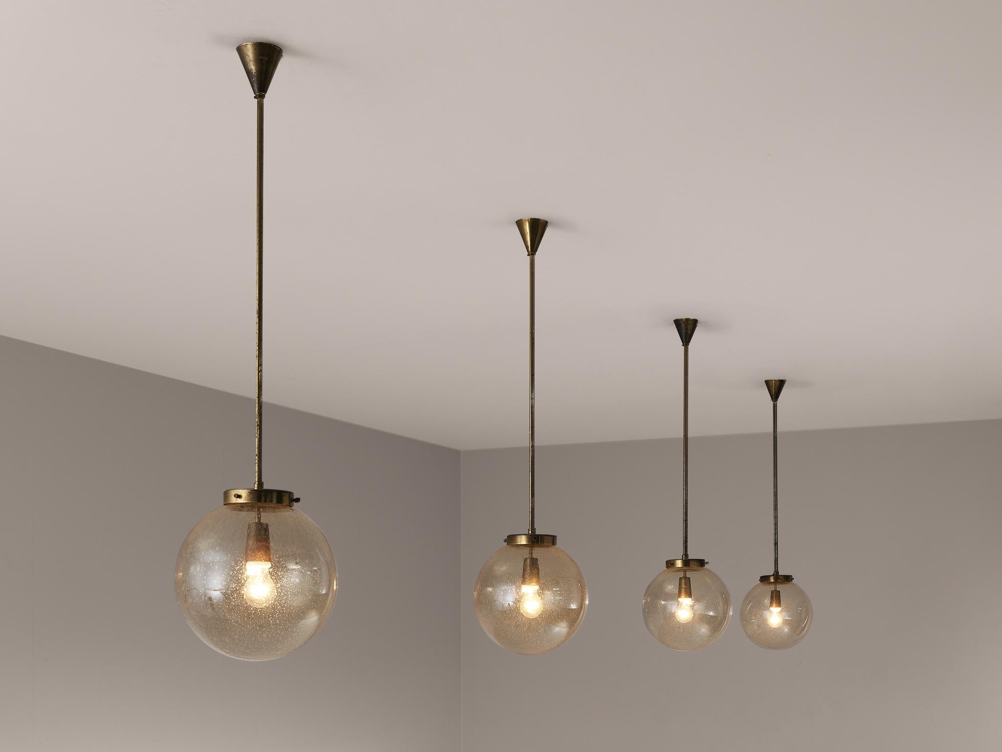 Pendants, glass, brass, Germany, 1960s.

This set of pendants features a smoked hand-blown glass orb. As a result of the hand-blown production technique, multiple bubbles are visible in the glass orb. It not only gives the shade a playful
