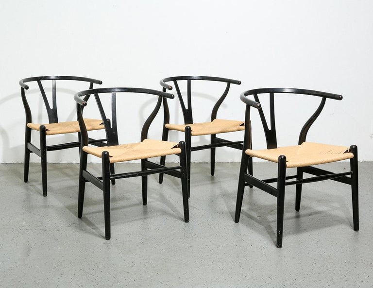 Set of 4 vintage 'Wishbone' side chairs designed by Hans Wegner for Carl Hansen & Søn, Denmark. Black lacquer frames with new papercord woven seats. Signed with original manufacturer's label.

Sold as a set of 4.