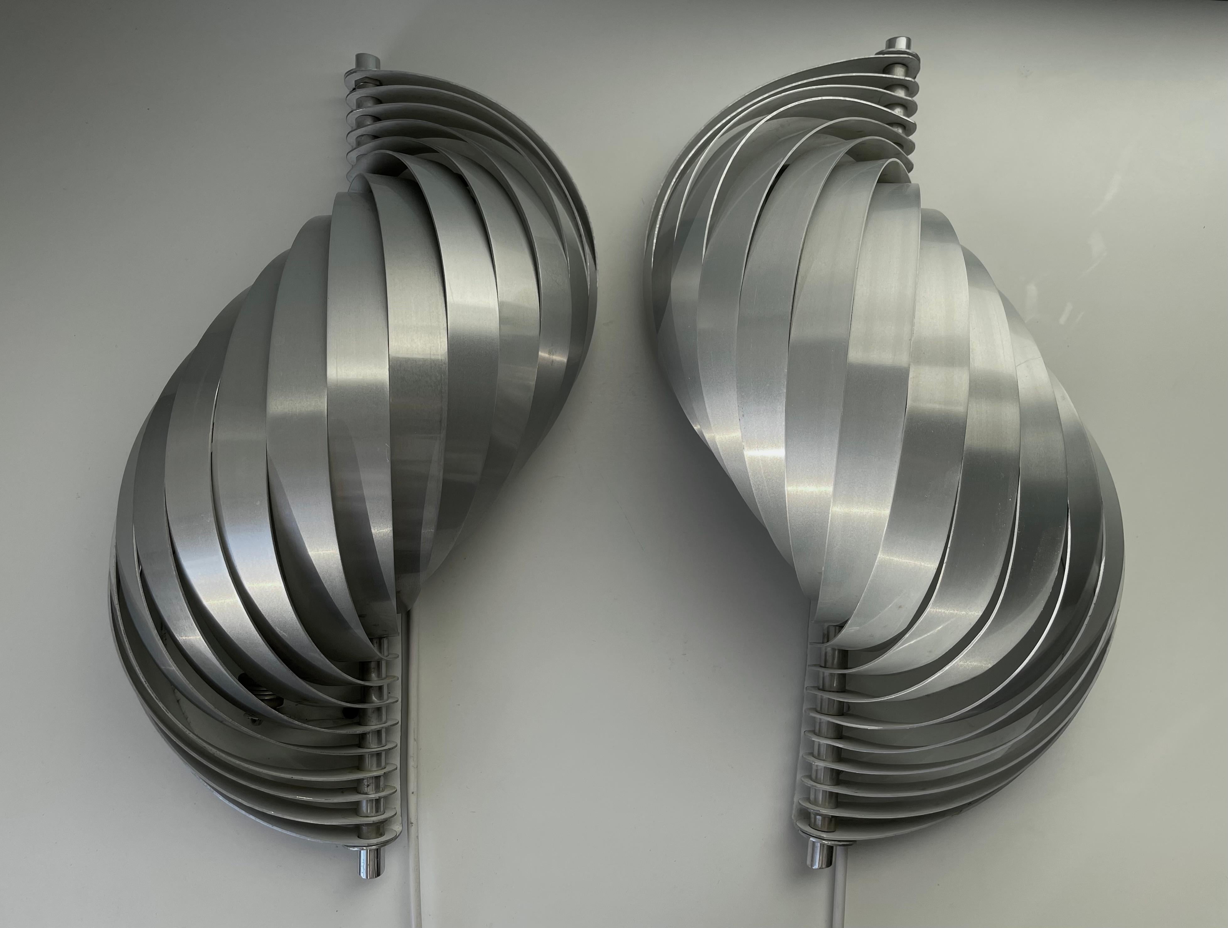 Stunning pair of shiny shell shaped aluminum futuristic wall sconces by French designer Henri Mathieu in the early 1970s. Brushed softly bent silver colored aluminum lamels compose this set of sculptural space age lights. Mounted on metal plate and