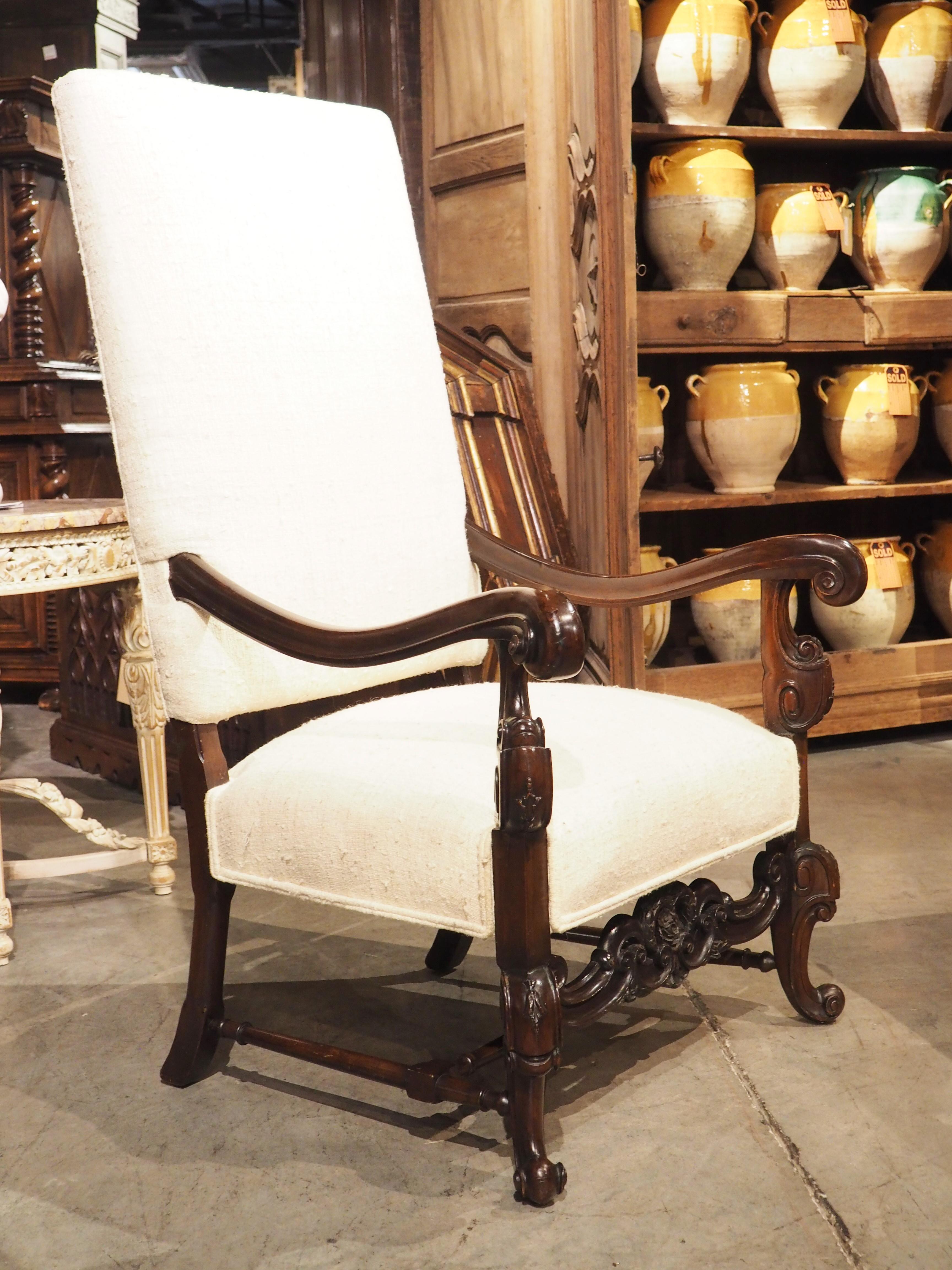 The highly decorative nature of Baroque-style furniture is prevalent on this set of carved armchairs with raw silk upholstery. Although not a true pair (the carved elements are noticeably different), the chairs have been carved in a similar manner