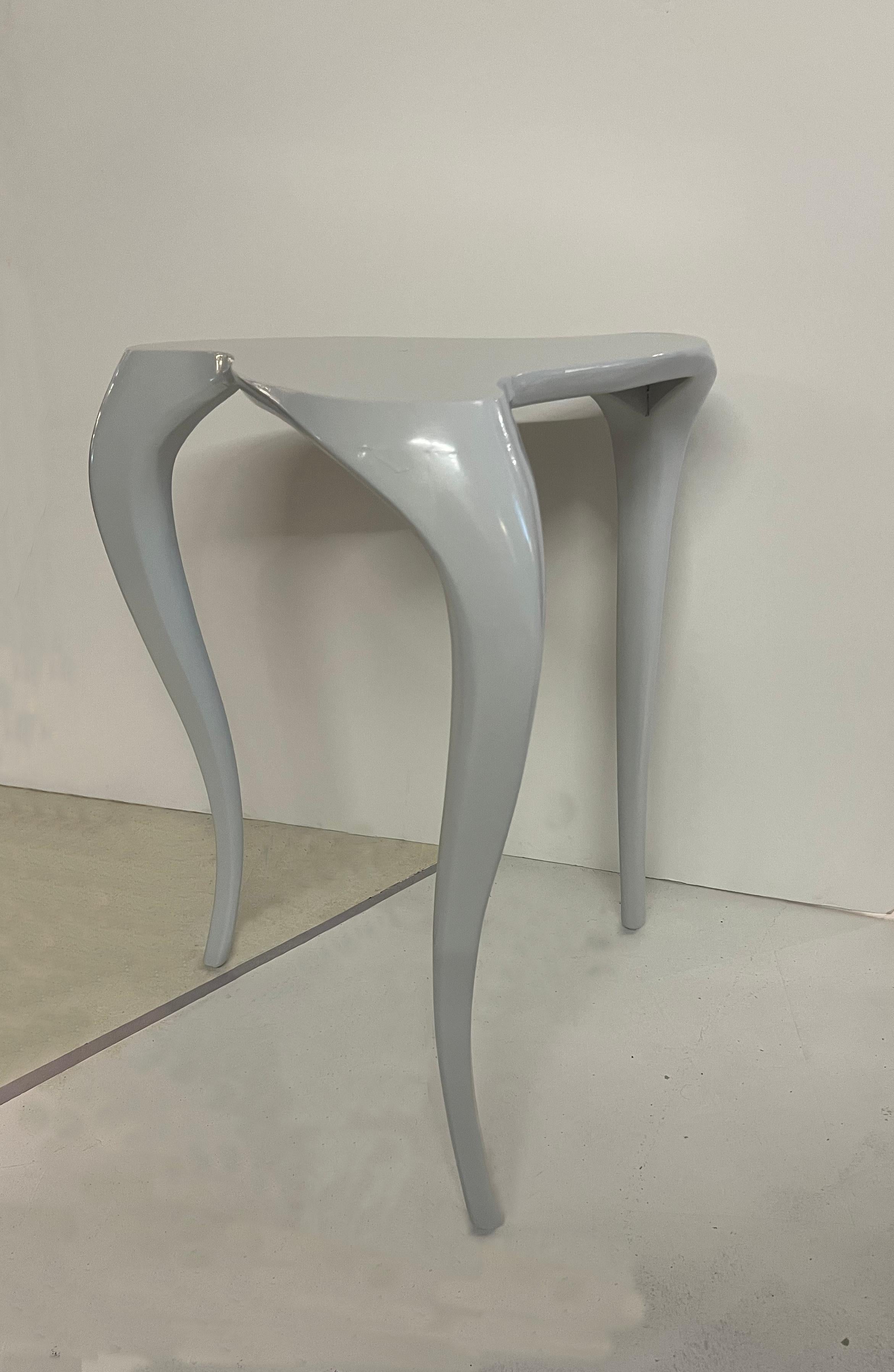 Incredible pair of Hollywood Regency light grey lacquer side tables. They feature a very light grey lacquered body with a curved design on the top and three undulated legs.
The grey color is so light that following the light around them, they can