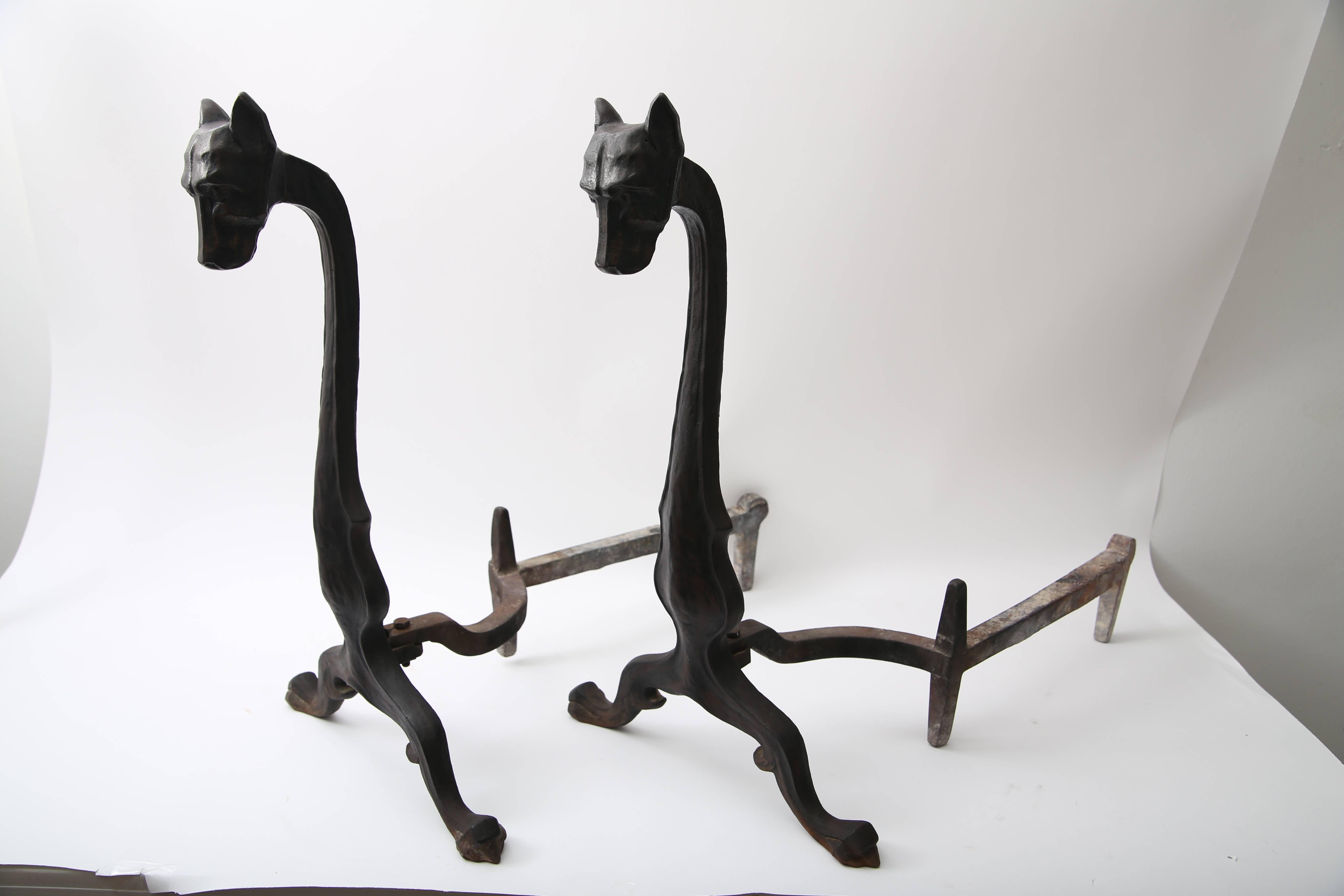 This pair of Art Deco style andirons were created by Bradley and Hubbard and are fabricated in hand-forged iron in the form of stylized dogs (hounds). 

FYI: 
Bradley & Hubbard Manufacturing Company
Fate Sold to the Charles Parker Company
Founded