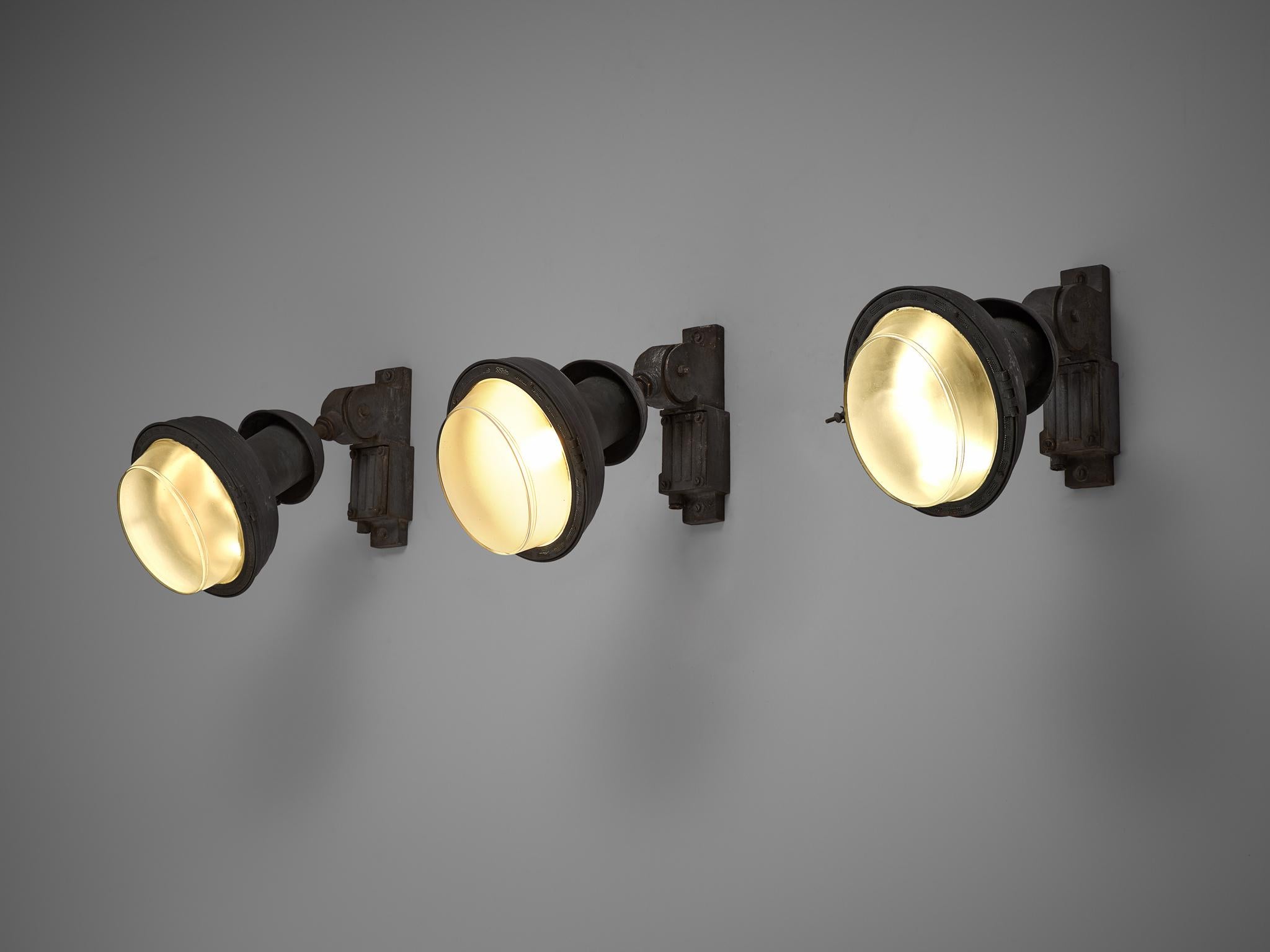 Set of industrial wall lamps, Europe, 1950s.

Heavy industrial wall lamps in metal. The lamps are made with several rounded elements, with a tapered shade in structured glass. The light shining through the shades is diffuse and soft. The heavy,