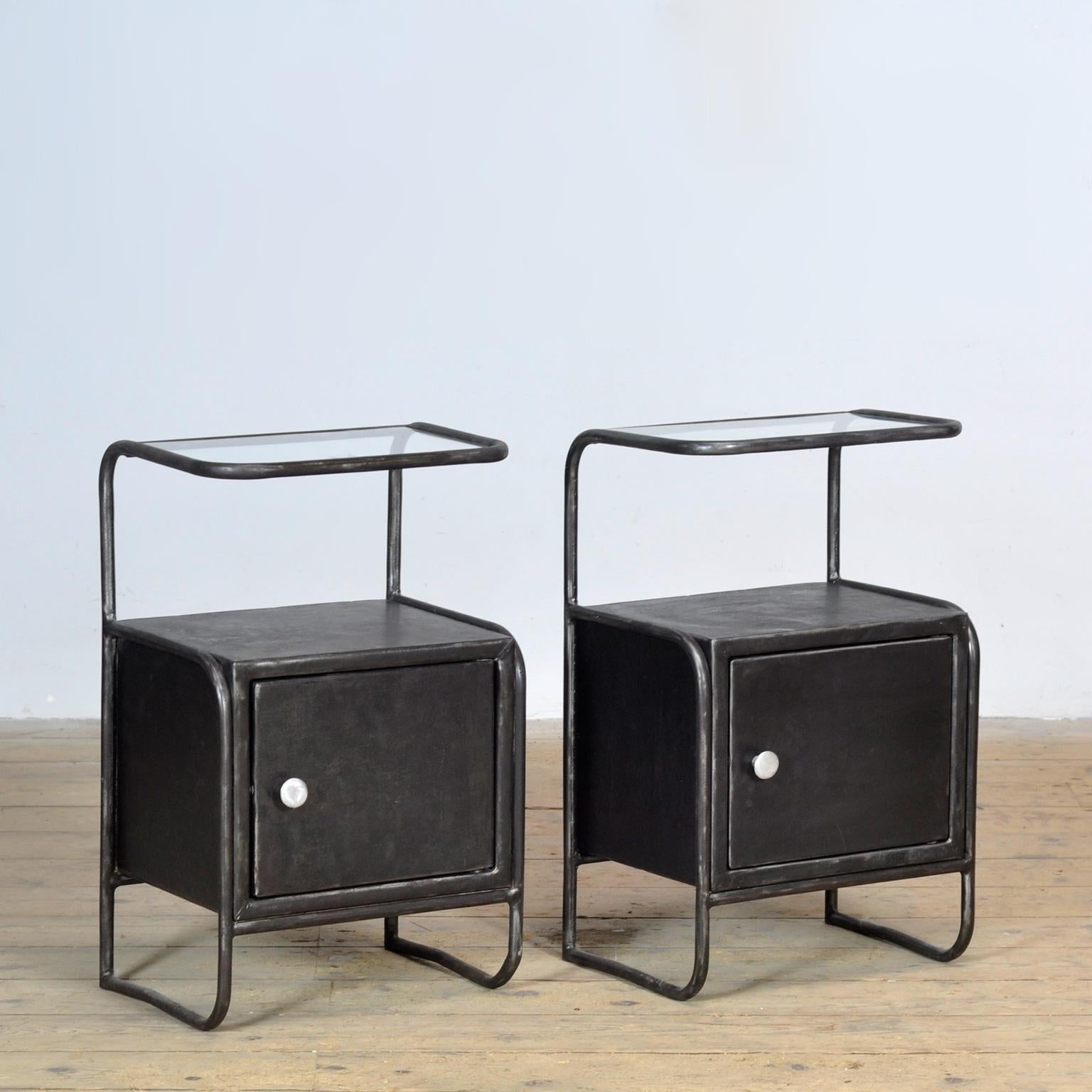 Questo set di comodini in ferro con piano in vetro trasuda storia e stile. Provenienti da un ospedale degli anni '50, sono state completamente sverniciate, accuratamente lucidate e trattate per proteggere dalla ruggine. Il risultato è un look