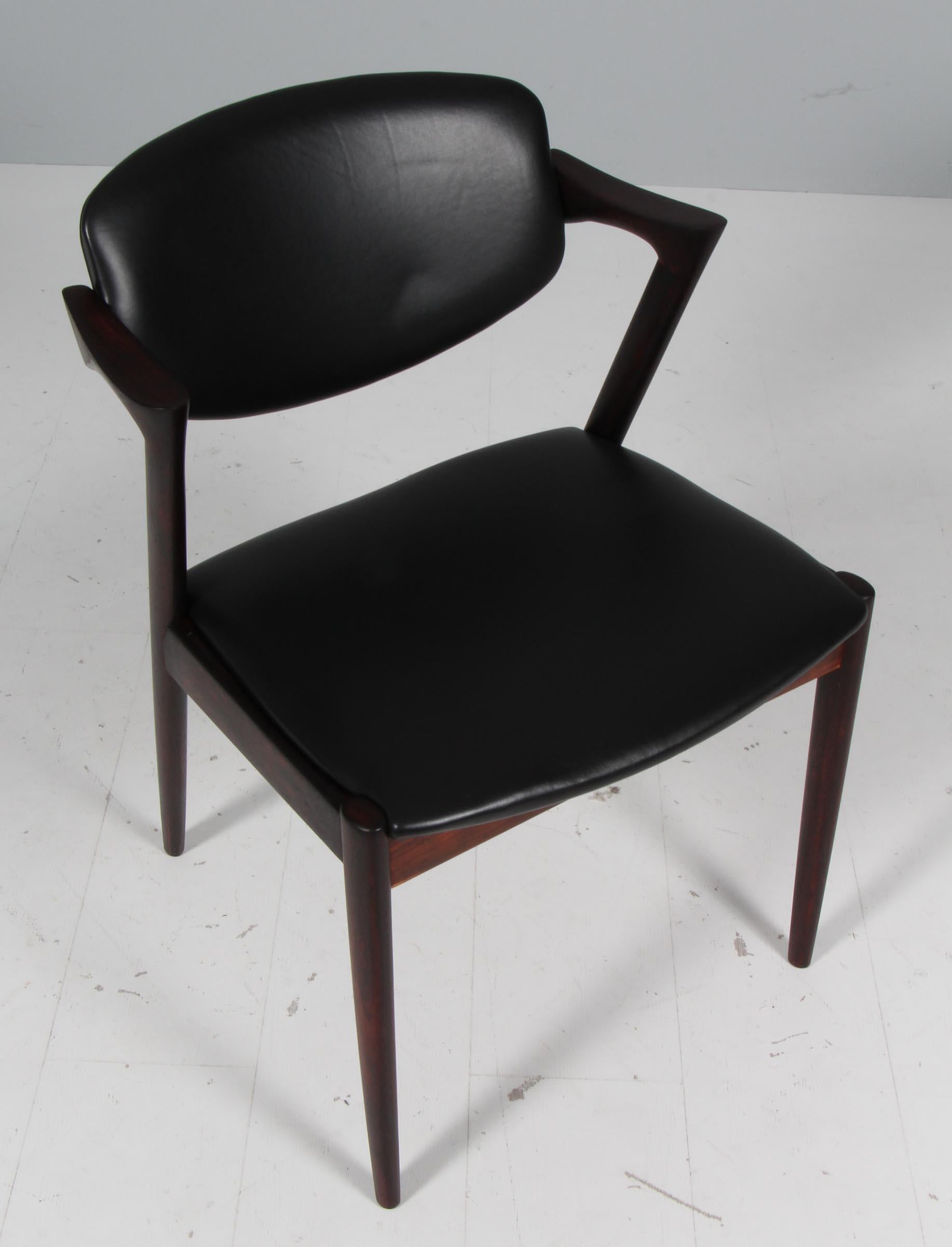 Ensemble de chaises de salle à manger produites par Skovman Andersen pour le grand magasin Illum Bolighus à Copenhague. Structure en bois de rose, assise et dossier recouverts de cuir aniline noir. Le pad du dossier est doté d'une fonction