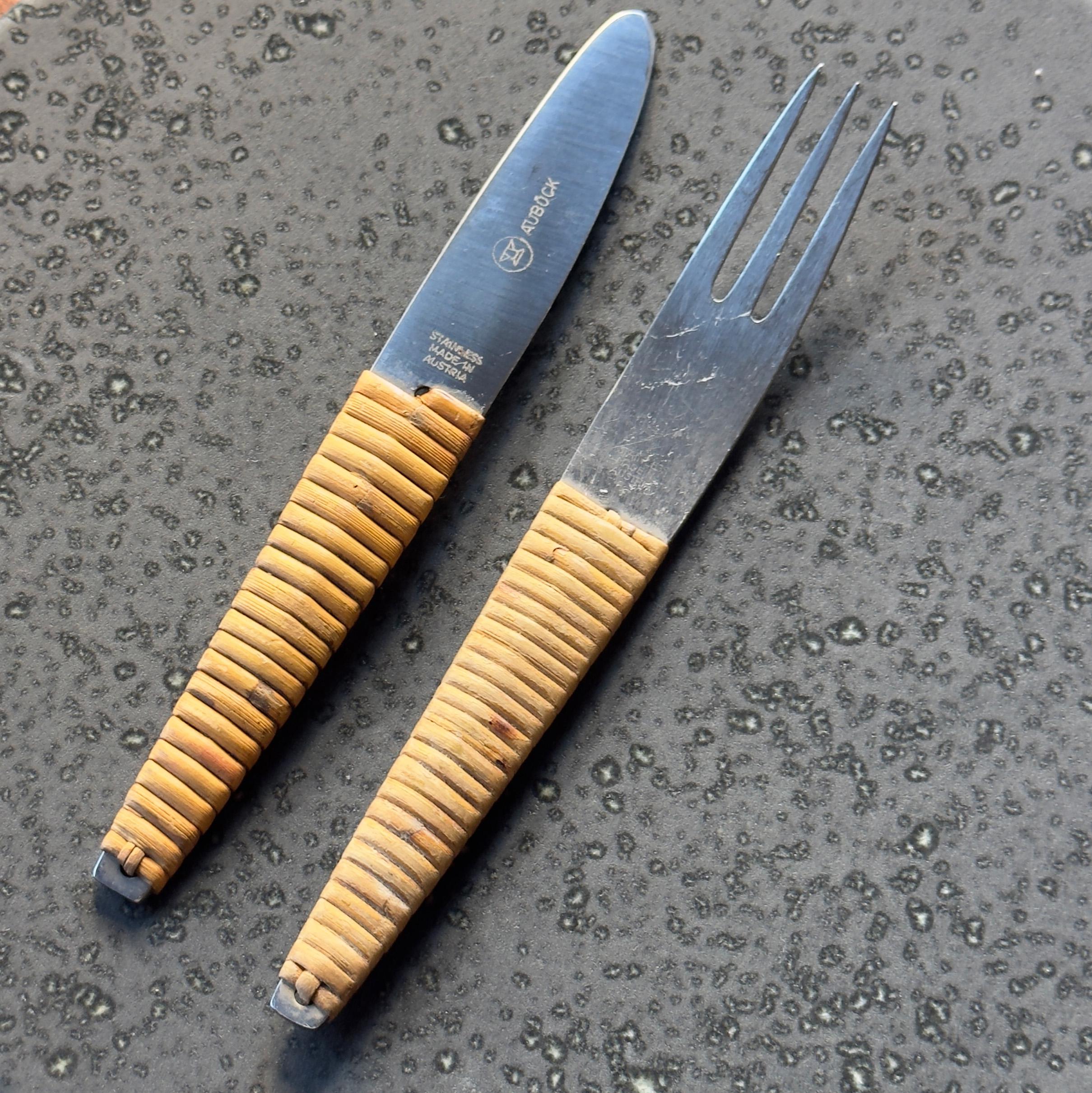 Description:

A vintage knife and fork set made by the Auböck Workshop, Vienna, circa 1950.

The body of the cutlery is made from stainless steel with the handles of each piece bound with tightly wrapped cane. This combination of materials is a