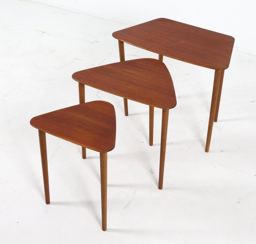 This charming set of nesting tables were designed by Kurt Ostervig for Jason Mobler. Dating from the 1960s, this set of tables is an iconic piece of mid-century modern history. 

Two of the tables bear a whimsical 'guitar pick' shape, the rounded