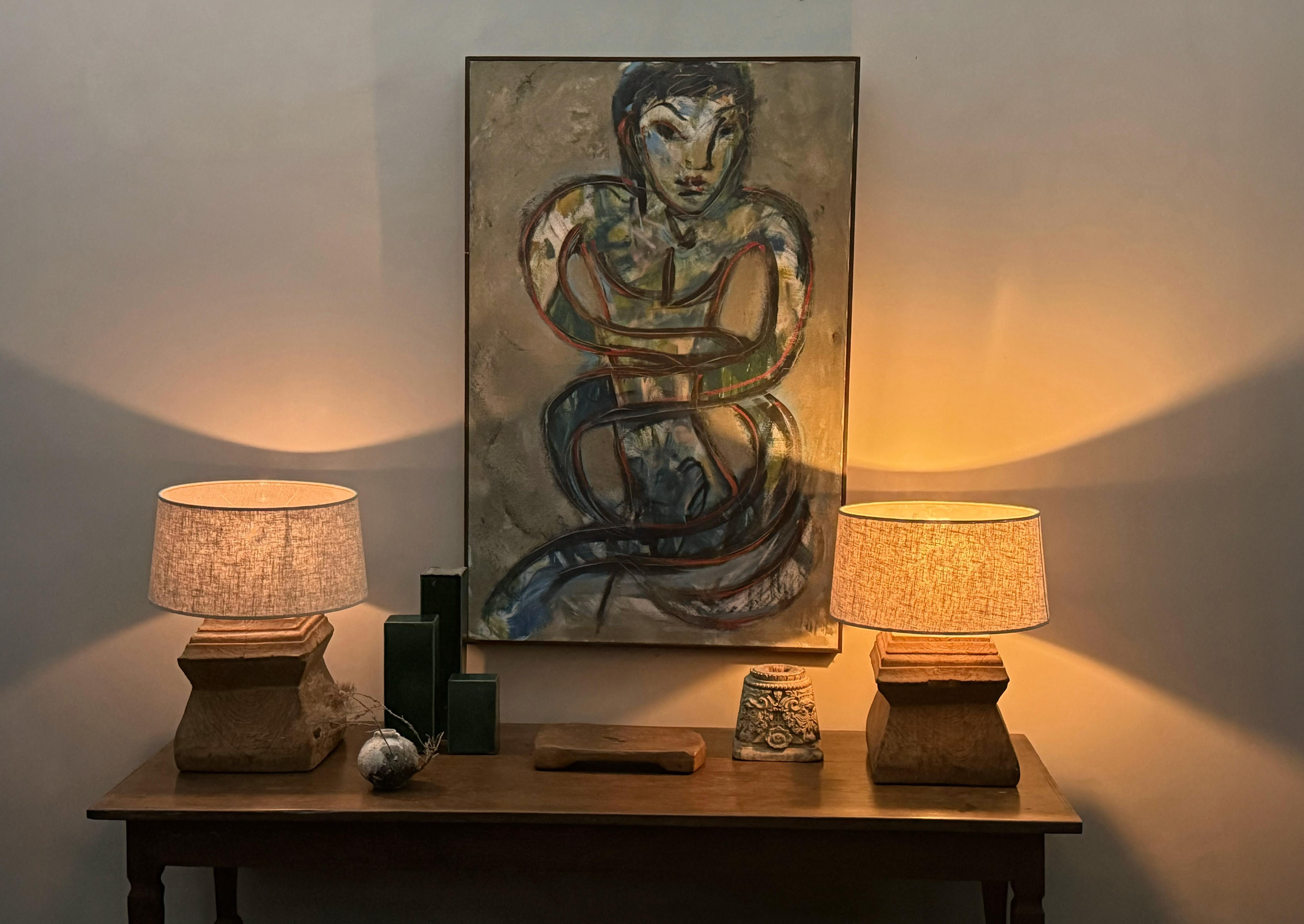 This striking pair of table lamps is crafted from antique Javanese column bases, thoughtfully repurposed to bring timeless character and sculptural elegance to contemporary interiors. Each base, hewn from richly textured hardwood, bears the marks of