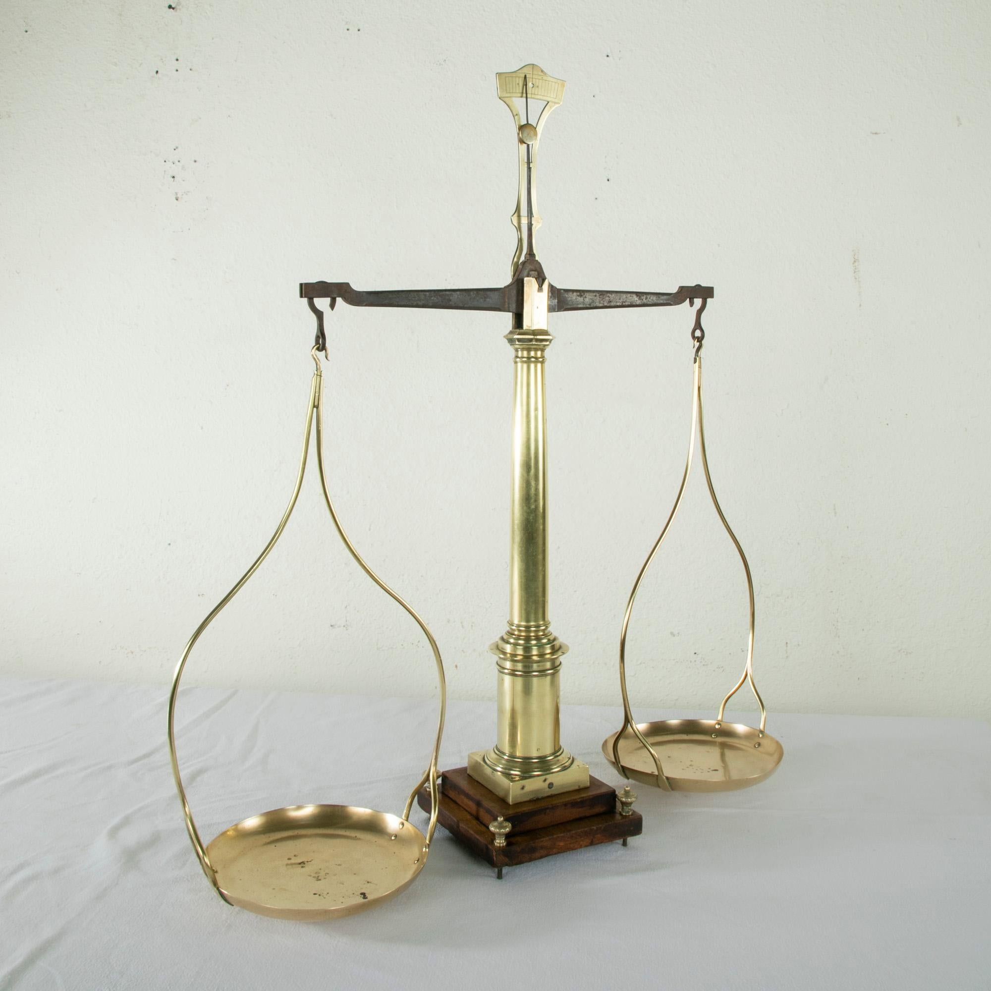 Standing at 31 inches in height, this set of large early 19th century French brass scales features two hanging brass pans that hang from an iron balance arm. The brass pans bear multiple stamps made by the French government to certify accuracy. The