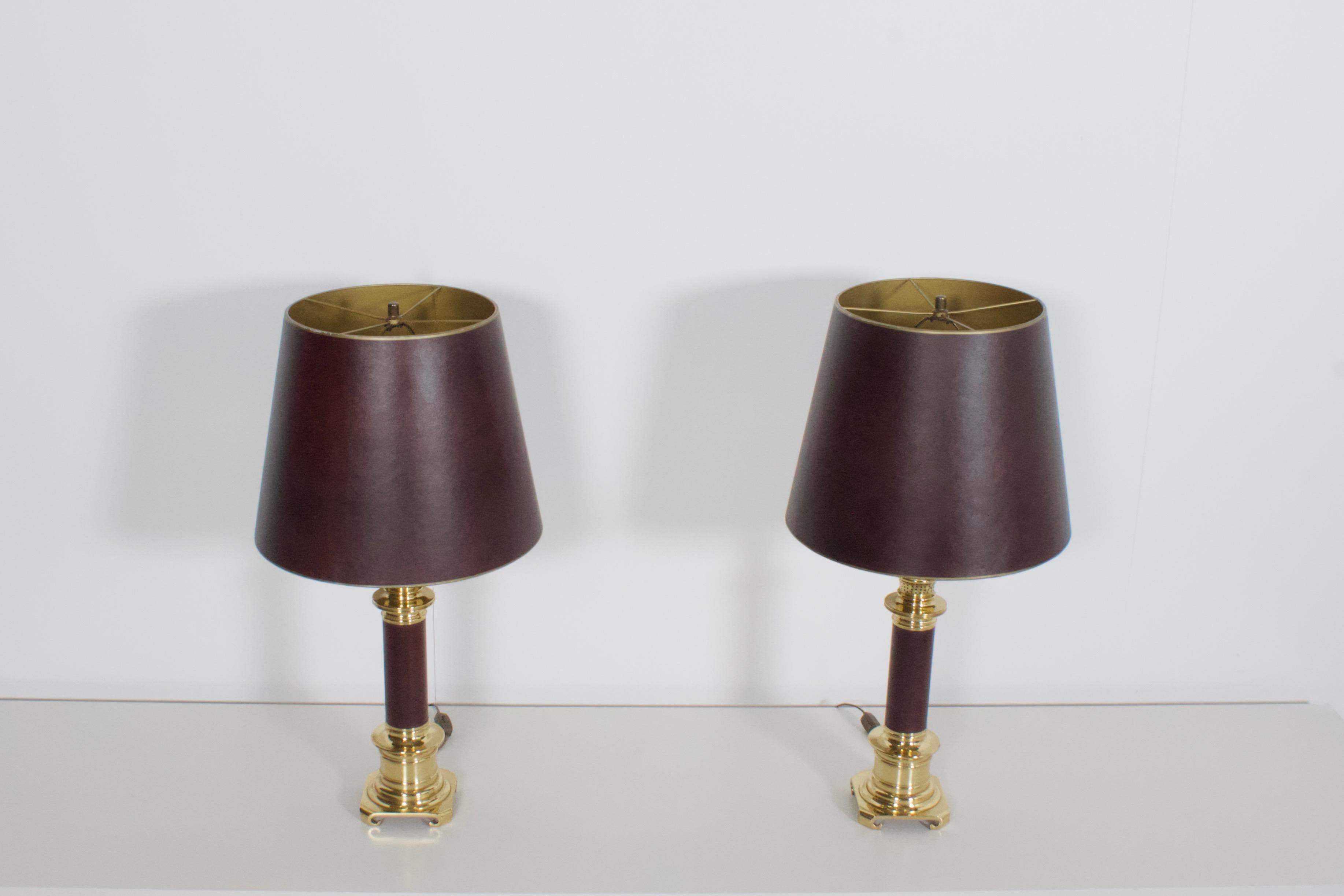 High quality neoclassical table lamps in very good condition.

Manufactured by Maison Jansen, France, 1970s

Heavy solid brass wrapped in a burgundy natural leather

The shades are also made in burgundy leather and they are gold on the